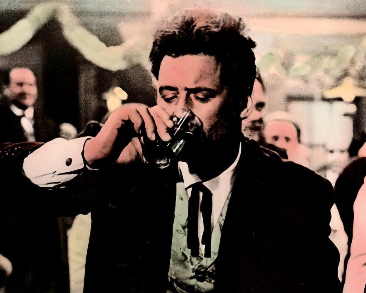 Ein Mann trinkt aus einem Glas in einer belebten Szene mit anderen Menschen.