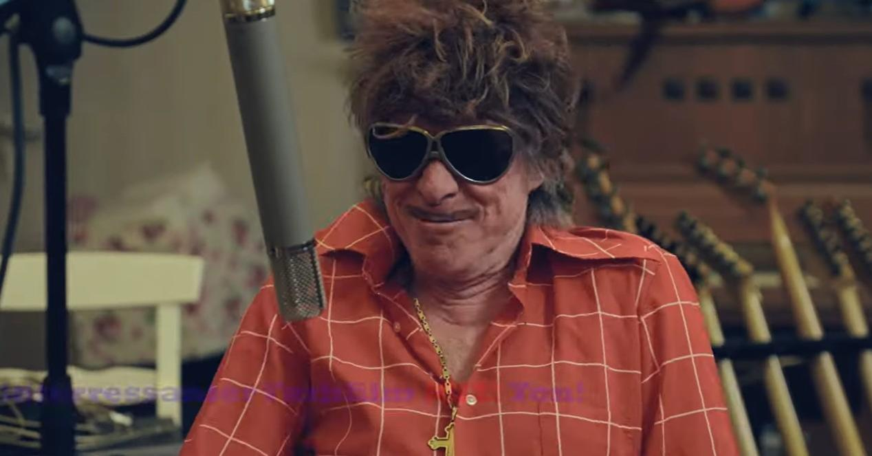 Mann mit Sonnenbrille und kariertem Hemd spricht in ein Mikrofon.