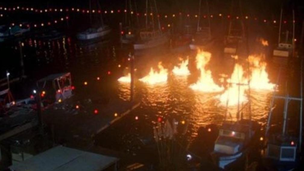 Boote in einem Hafen bei Nacht, brennendes Wasser, Lichterketten.
