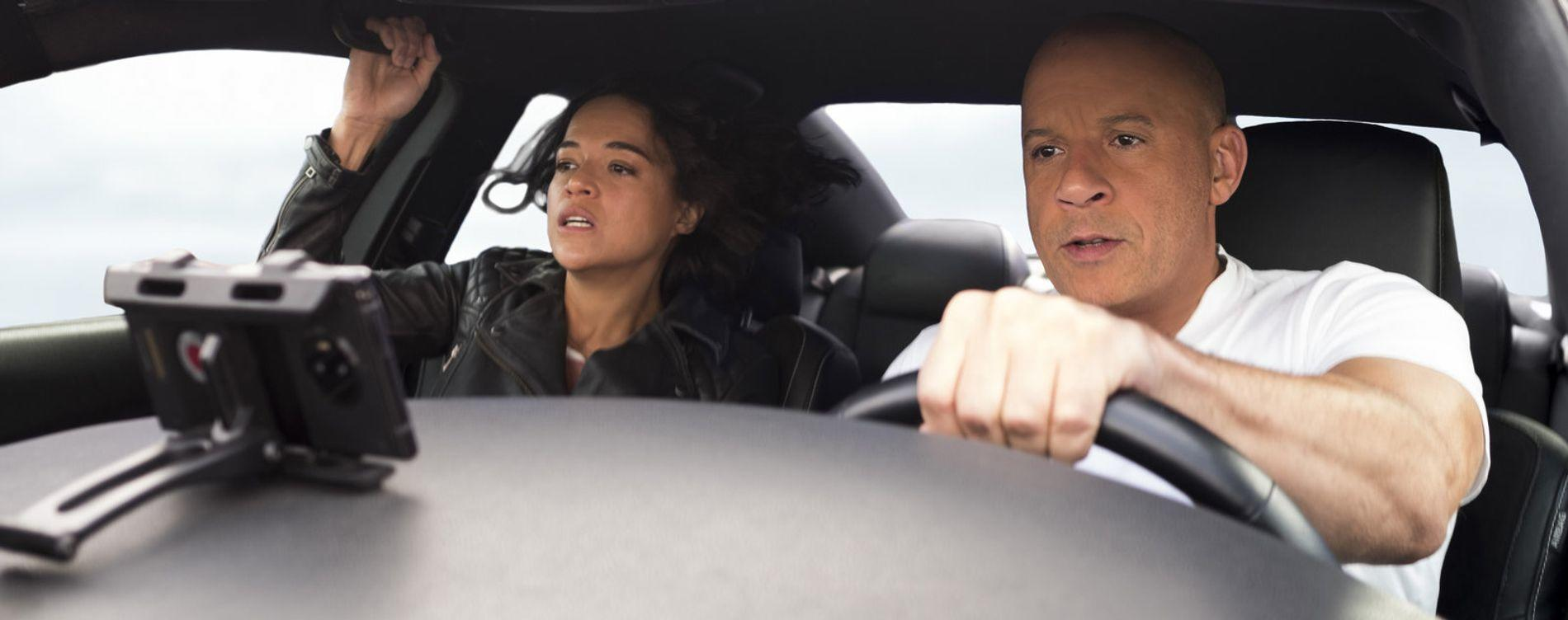 Mann und Frau fahren in einem Auto, Himmel im Hintergrund.