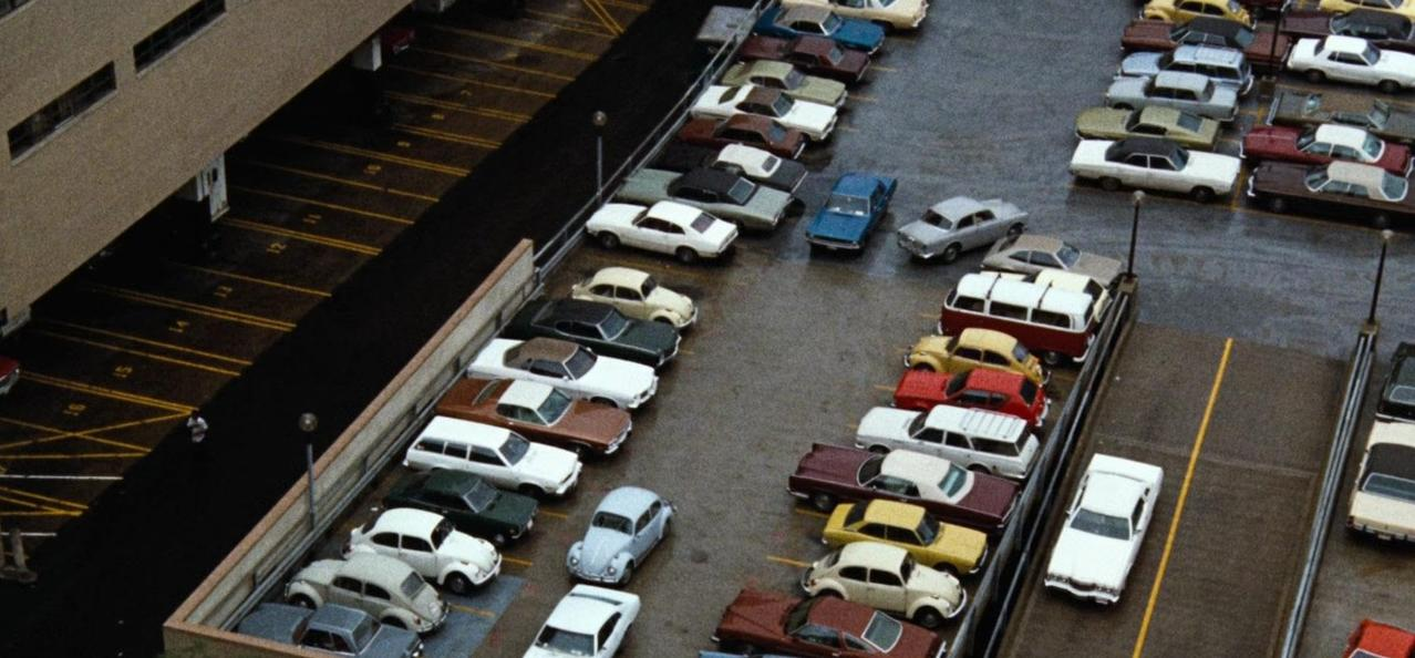 Ein Parkplatz mit vielen Autos und einem Gebäude.