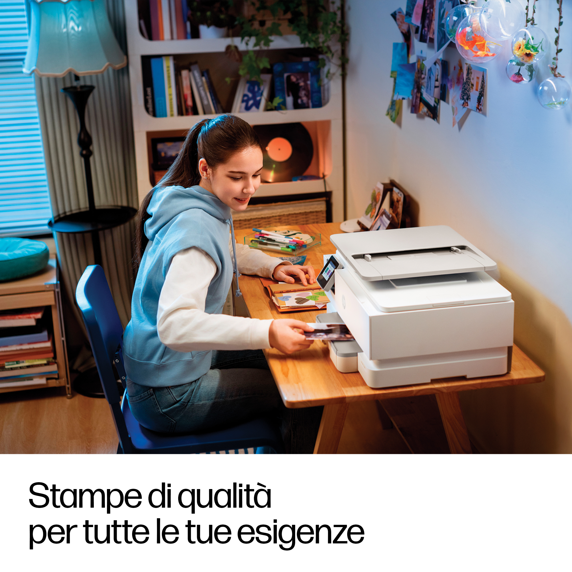 Ragazza inserisce foto in stampante, scrivania con lampada e libreria.