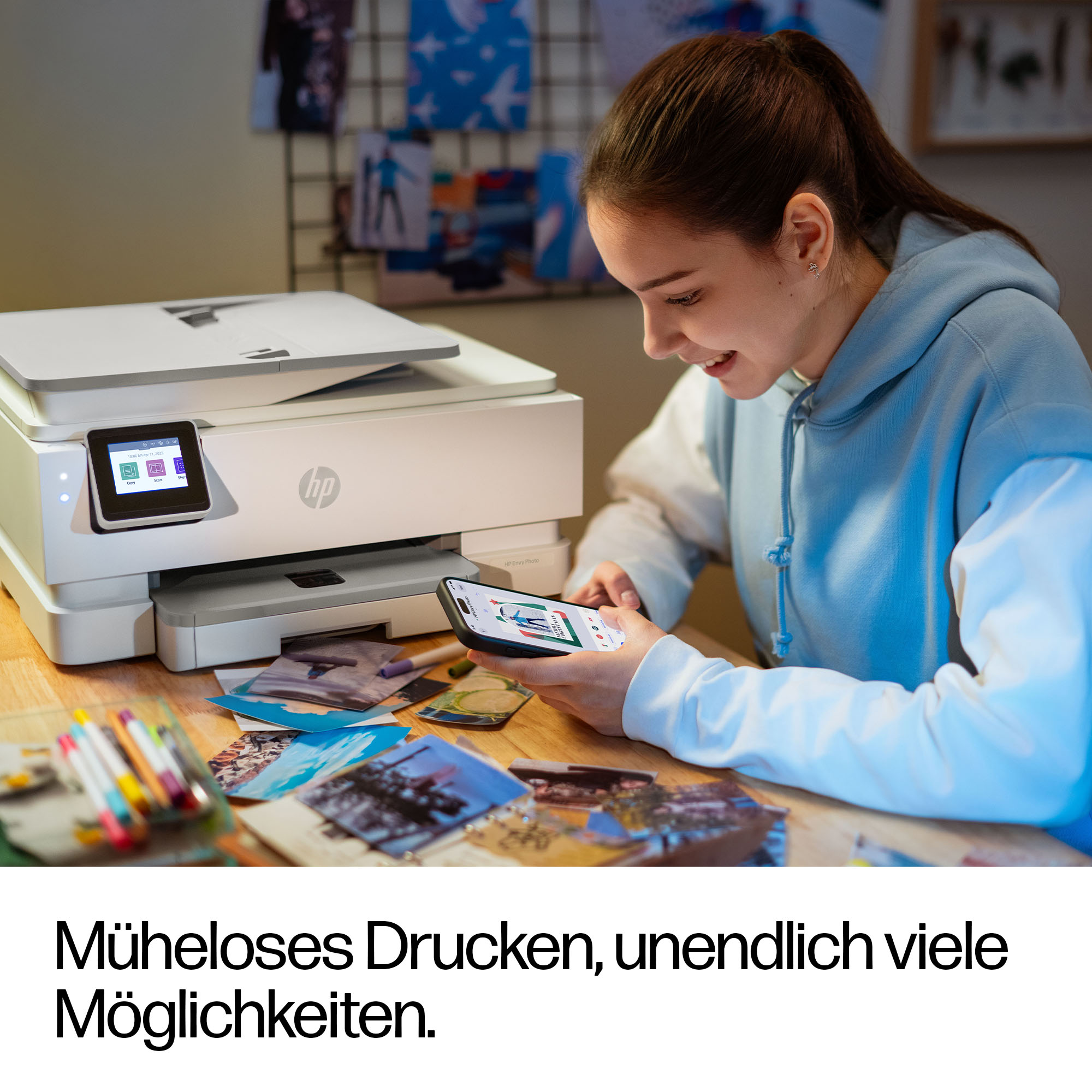 Eine junge Frau nutzt ihr Smartphone neben einem HP Drucker. Fotos liegen auf dem Tisch.