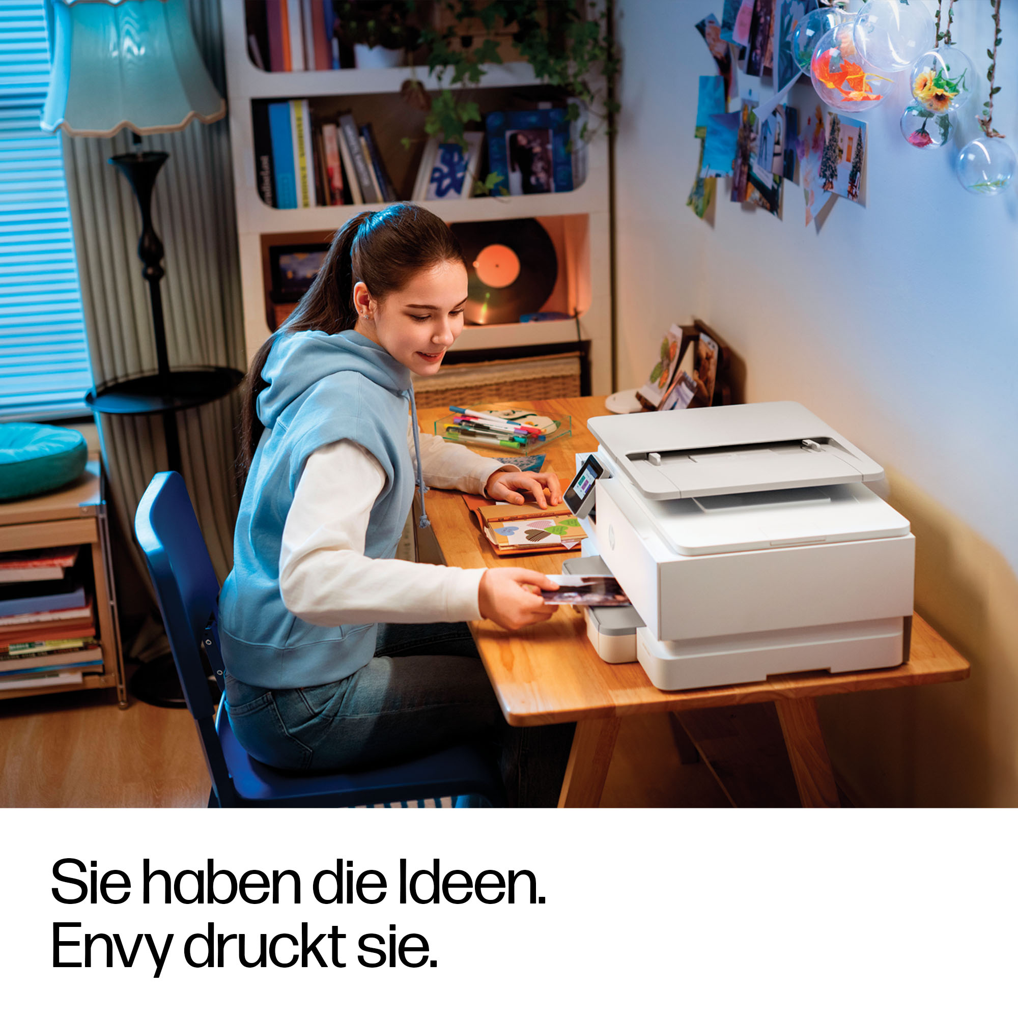 Eine junge Frau druckt Fotos an einem Schreibtisch. Ein Drucker steht auf dem Tisch.
