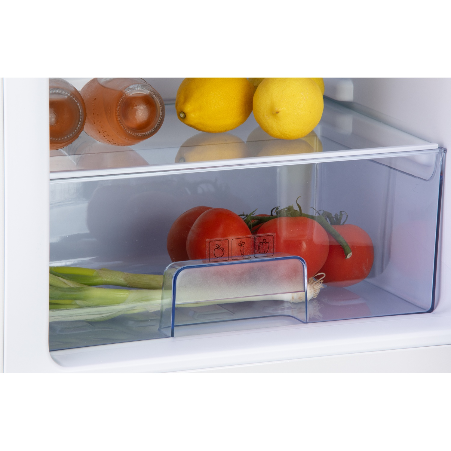 Bouteilles de boissons, citrons, tomates et oignons verts dans un réfrigérateur.