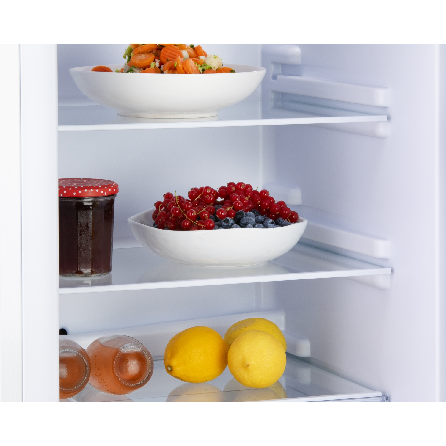 Légumes, baies, confiture et citrons dans un réfrigérateur.
