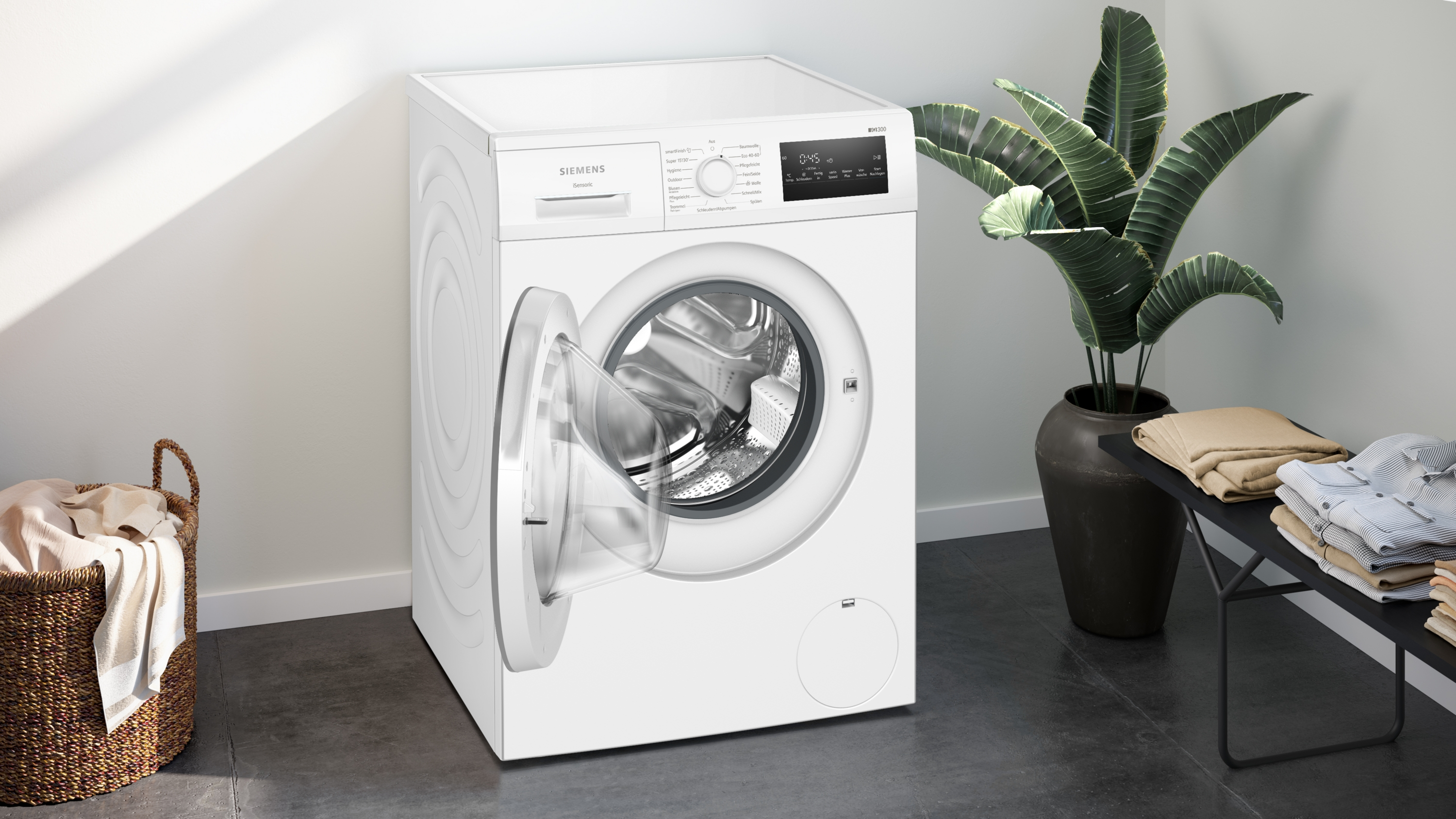Eine weiße Siemens Waschmaschine mit offener Tür steht neben einem Wäschekorb.