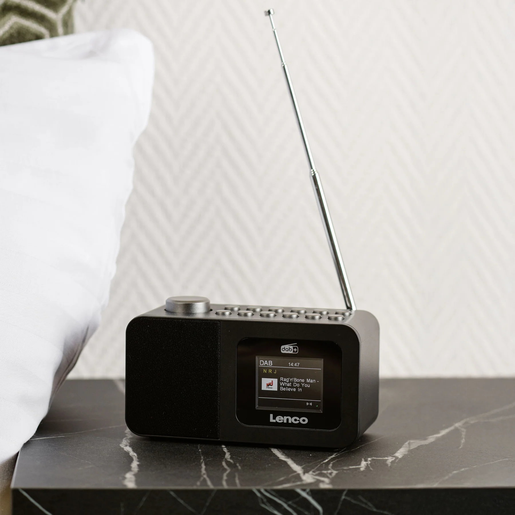 Une radio DAB+ noire avec antenne est posée sur une table en marbre.