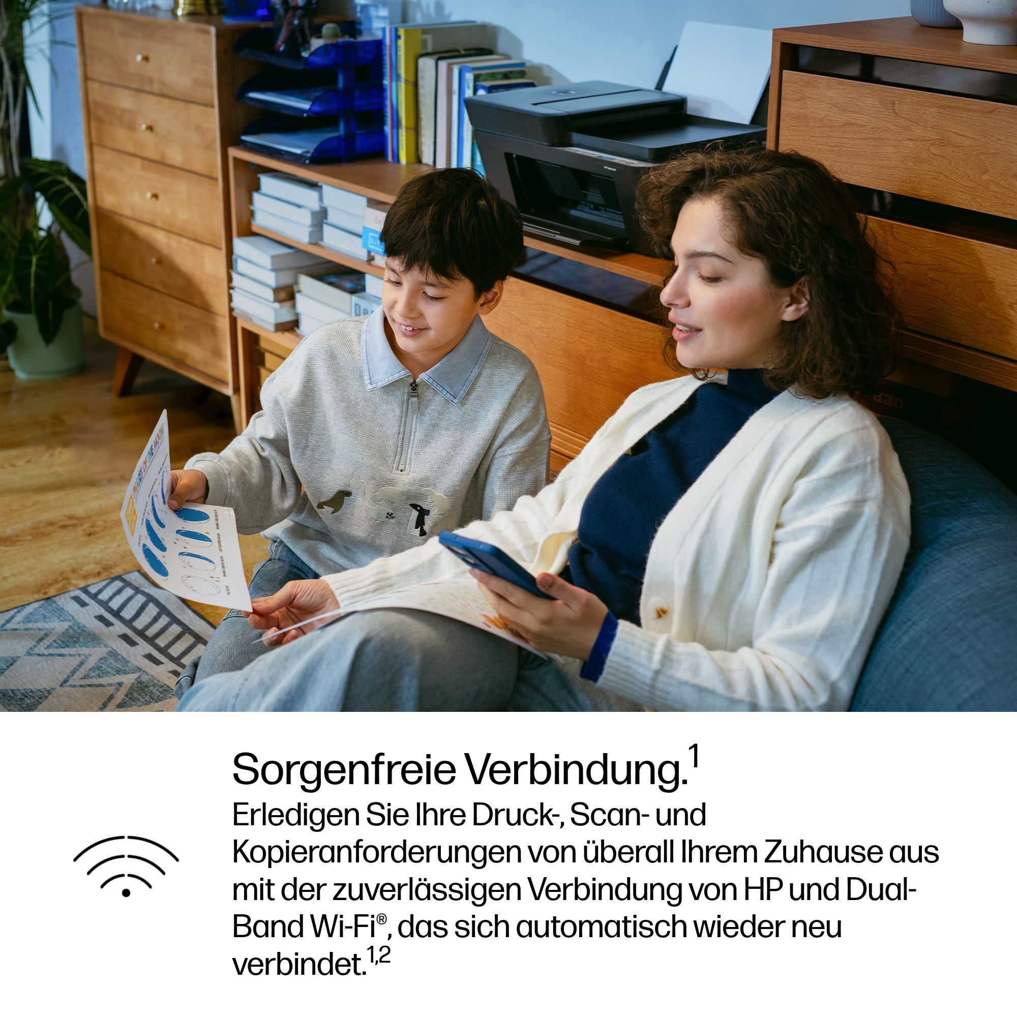 Frau und Kind schauen auf Dokumente und Handy. Drucker im Hintergrund.