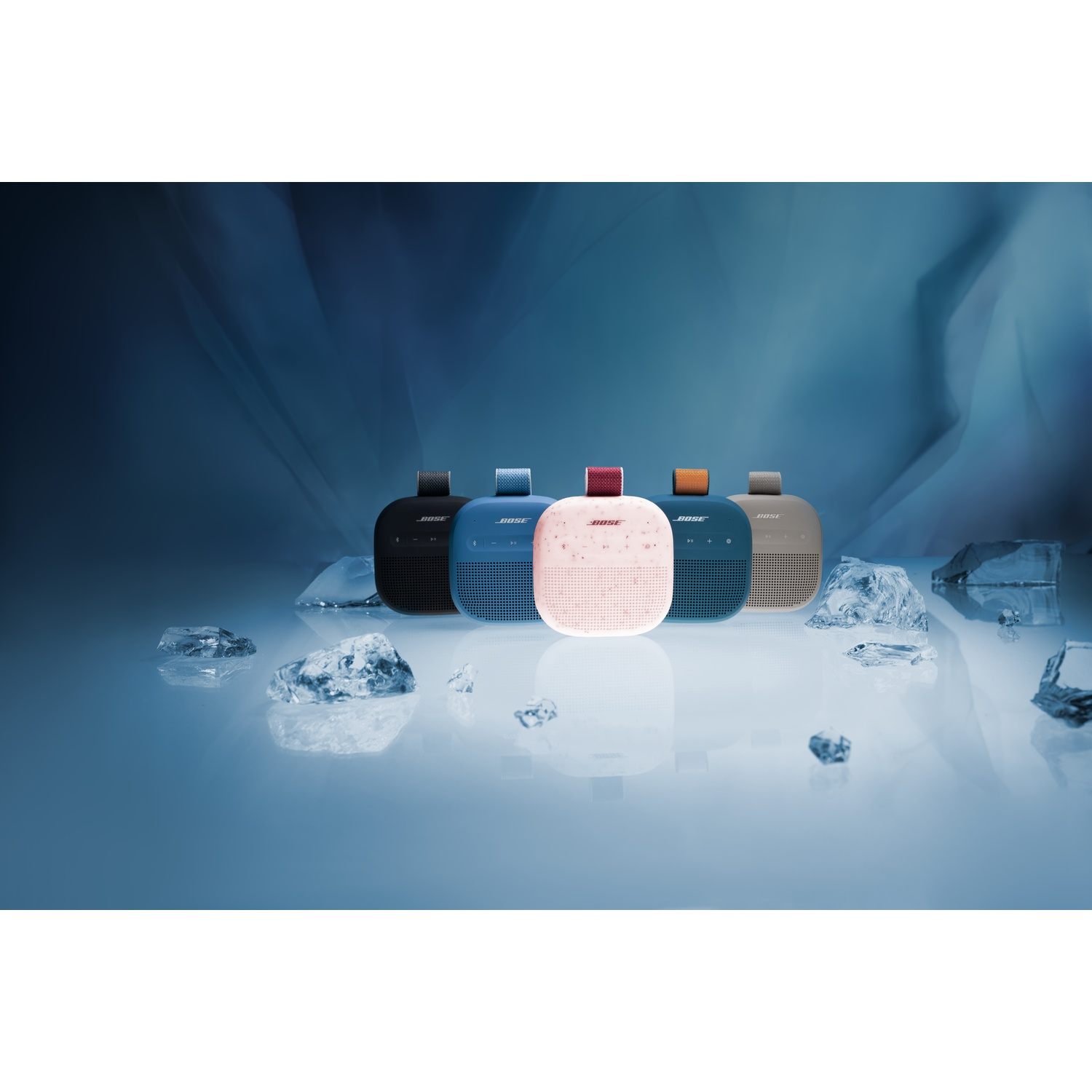 Cinque altoparlanti Bose neri, blu, rosa, turchese e beige disposti con cubetti di ghiaccio.
