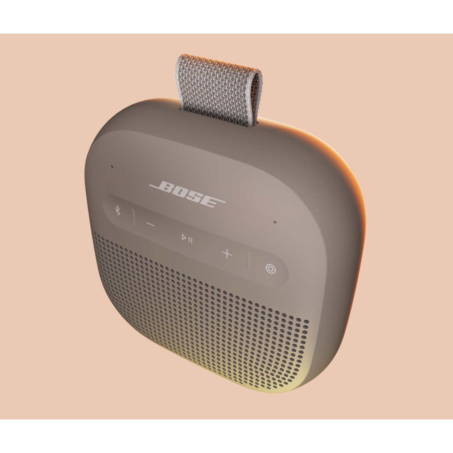 Un altoparlante Bose beige con tracolla in tessuto su sfondo arancione chiaro.