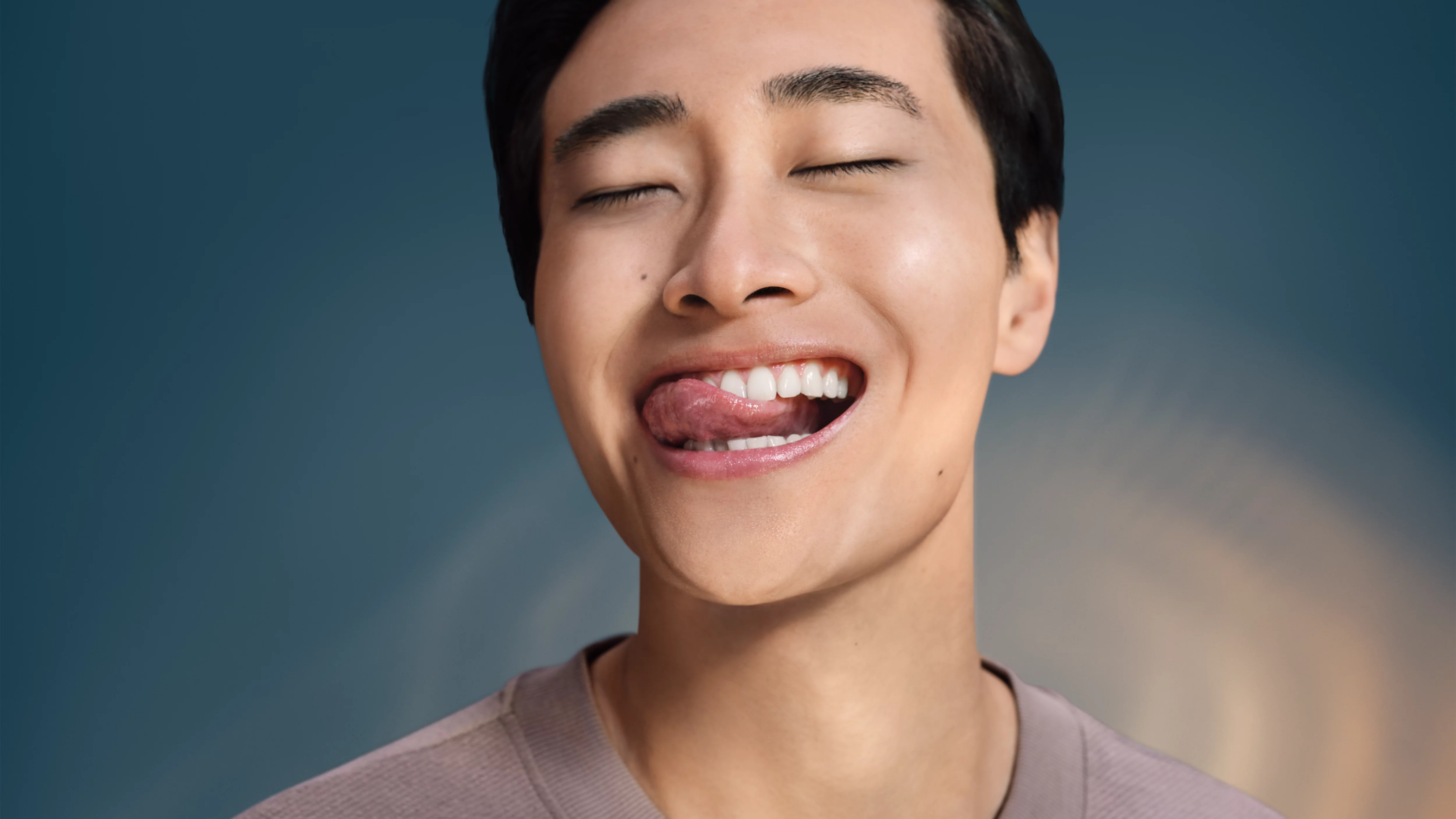 Mężczyzna z zamkniętymi oczami i wystawionym językiem, niebieskie tło.