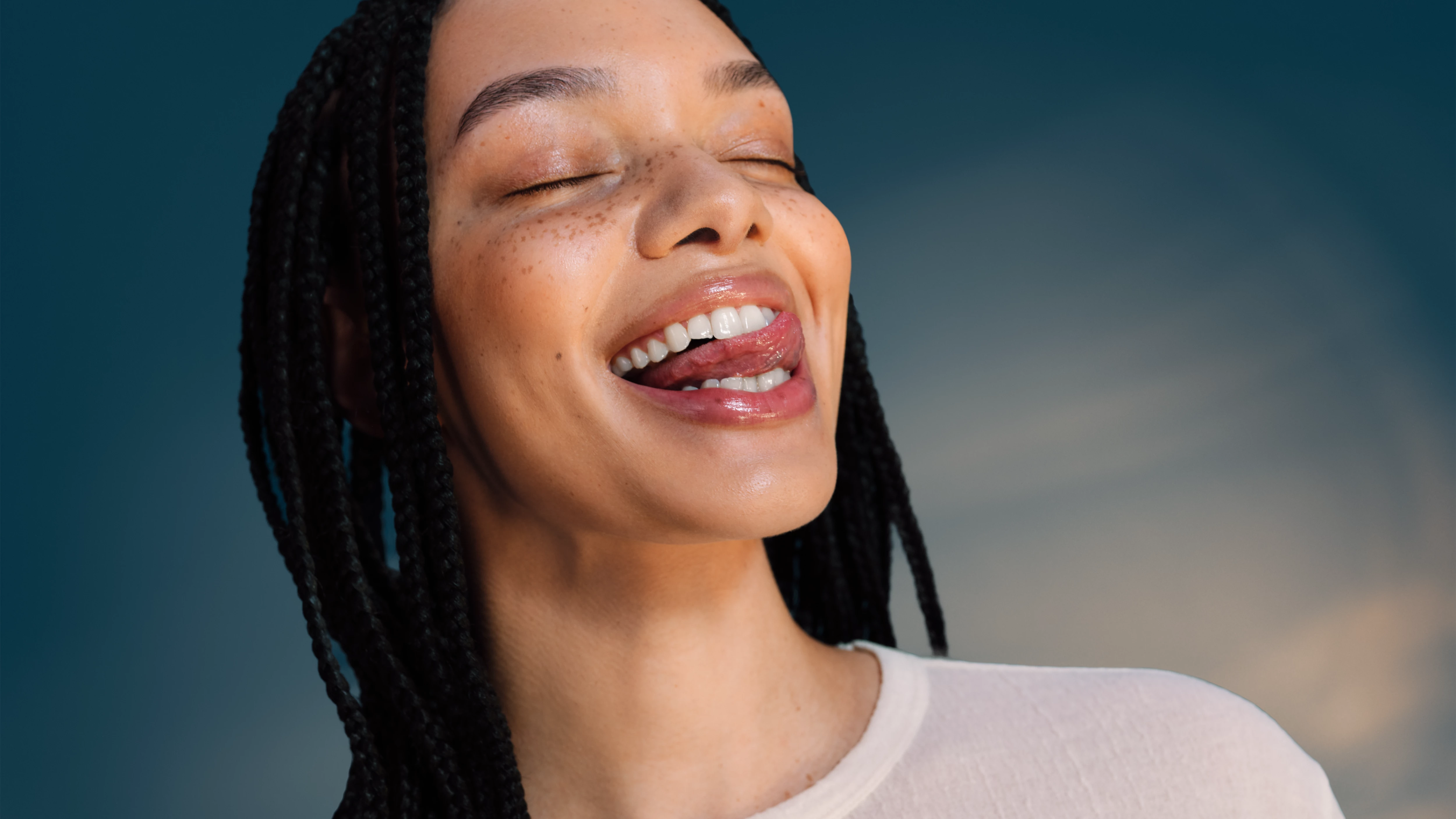 Kobieta z warkoczami wystawia język.