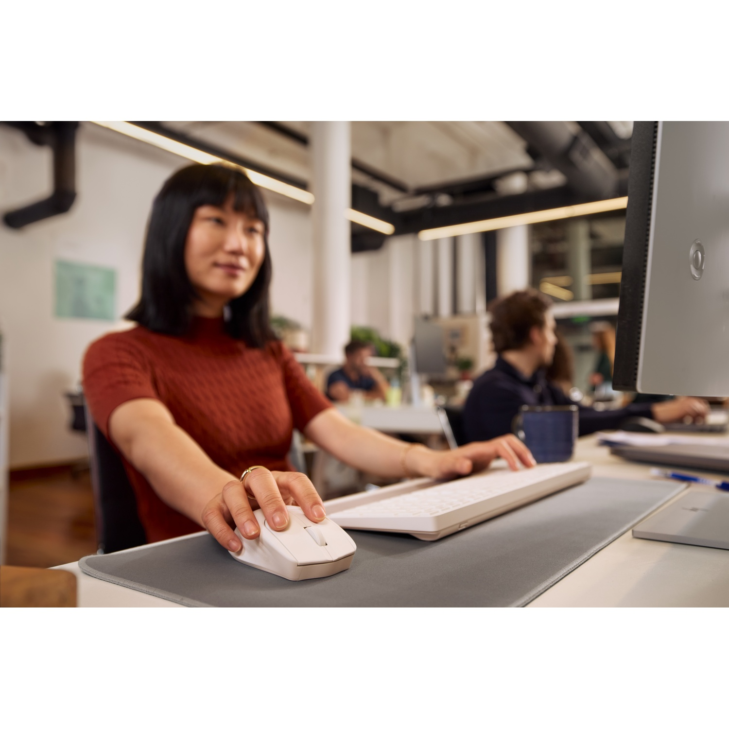 Woman using a mouse at a computer. Office in the background.