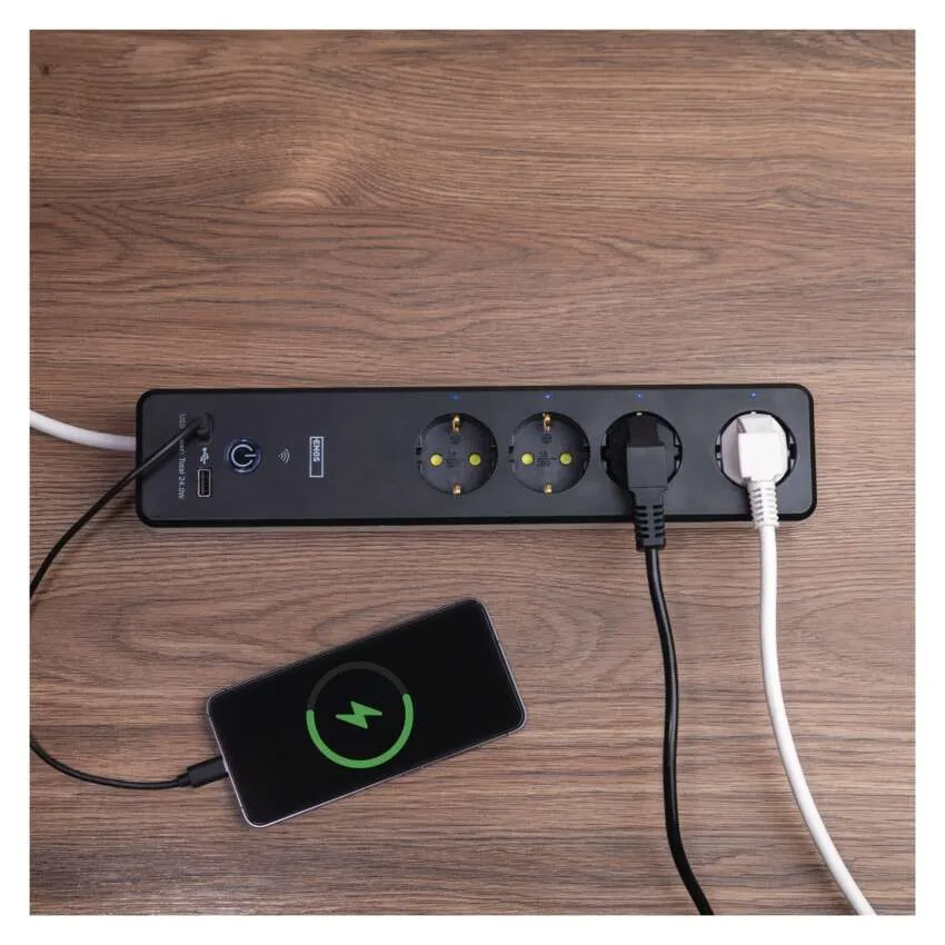 Egy fekete elosztó USB-portokkal, amely egy telefont tölt egy faasztalon.
