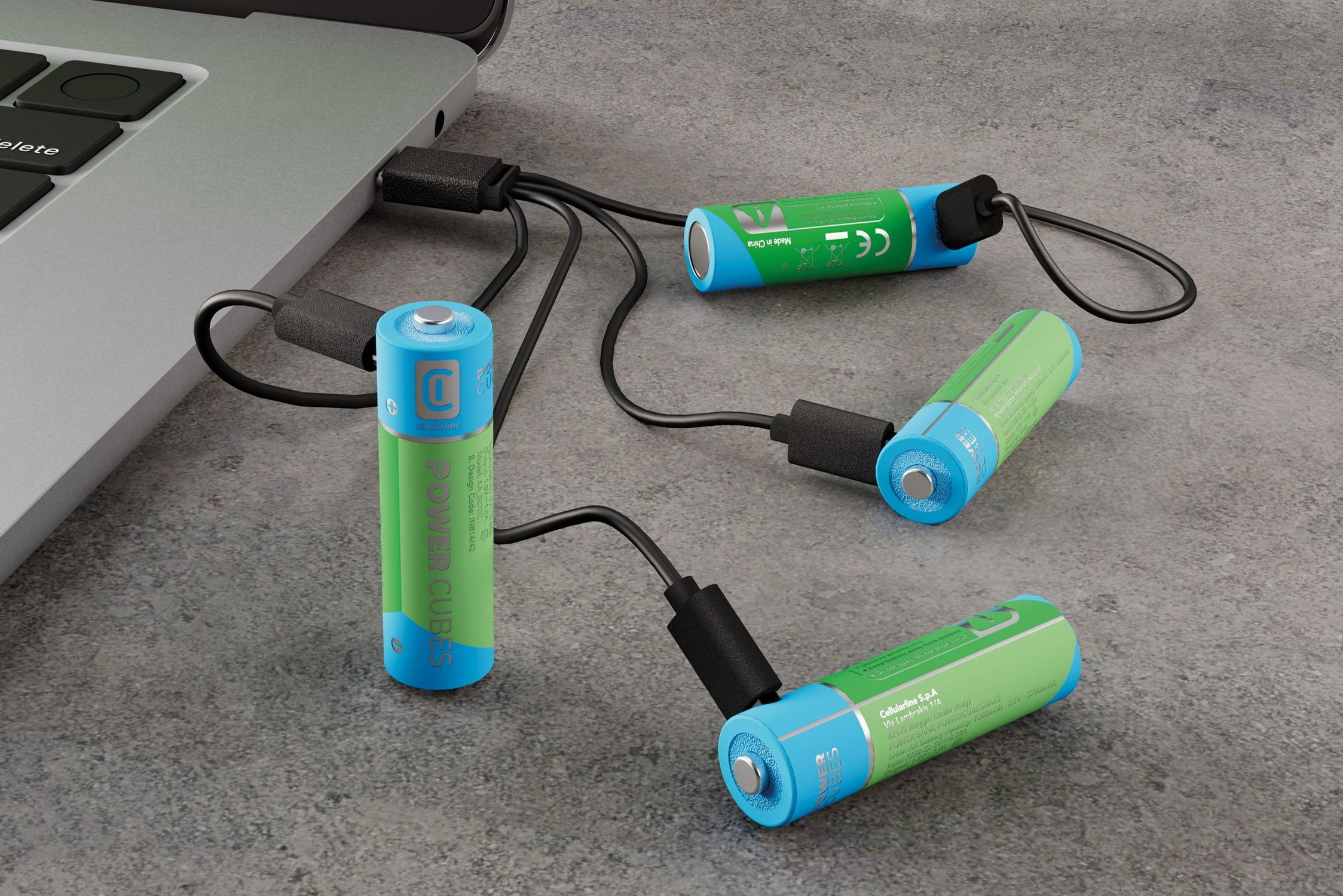 Cuatro pilas AA cargando vía USB desde un portátil. Pilas azules y verdes.
