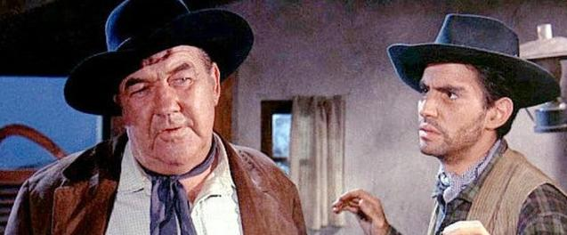 Zwei Männer in Cowboy-Kleidung mit Hüten. Der eine ist korpulent und trägt eine braune Jacke.