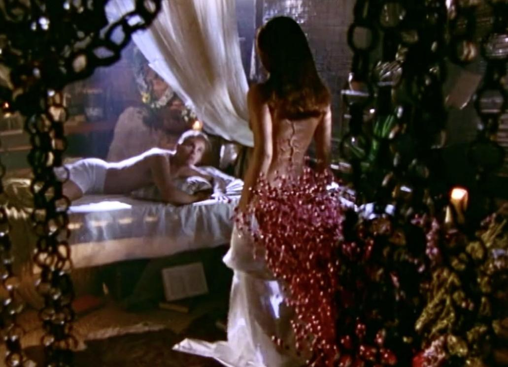 Mann liegt im Bett, Frau in rotem Kleid steht.