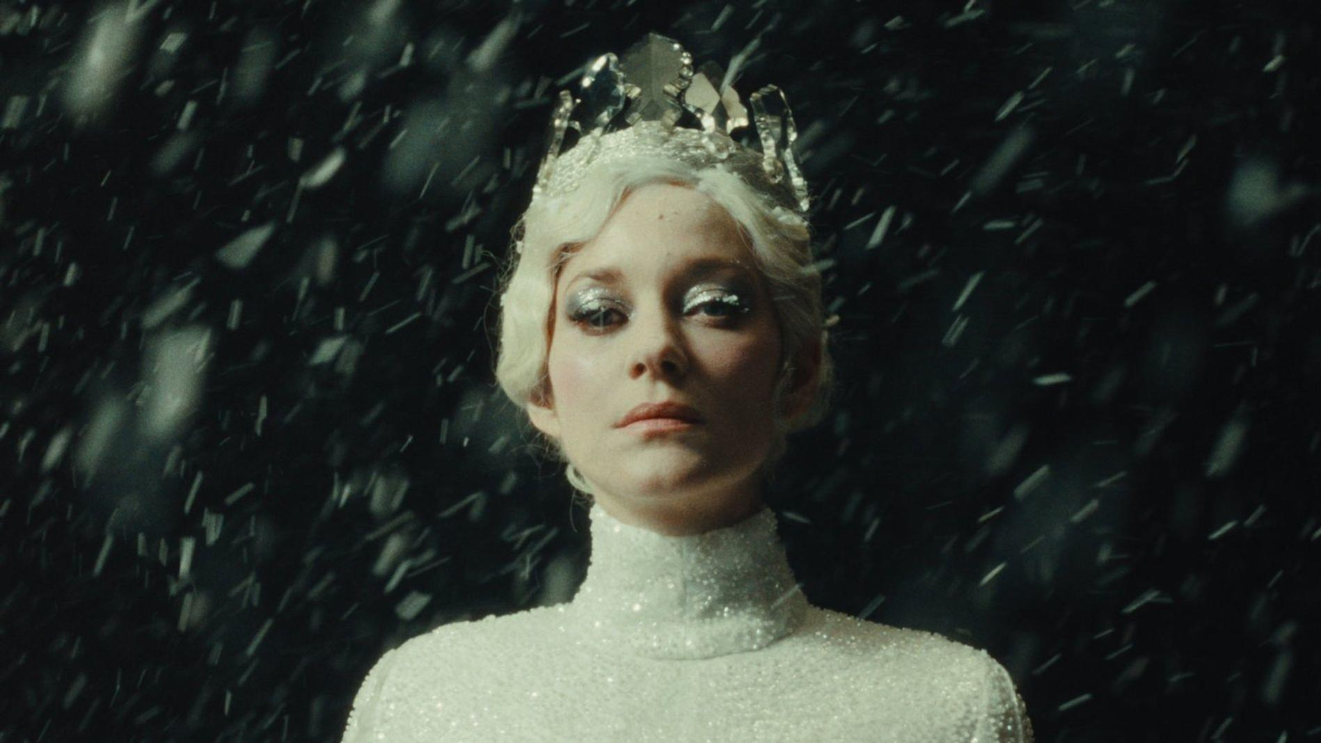 Eine Frau mit Krone und Glitzerkleid im Schneefall.