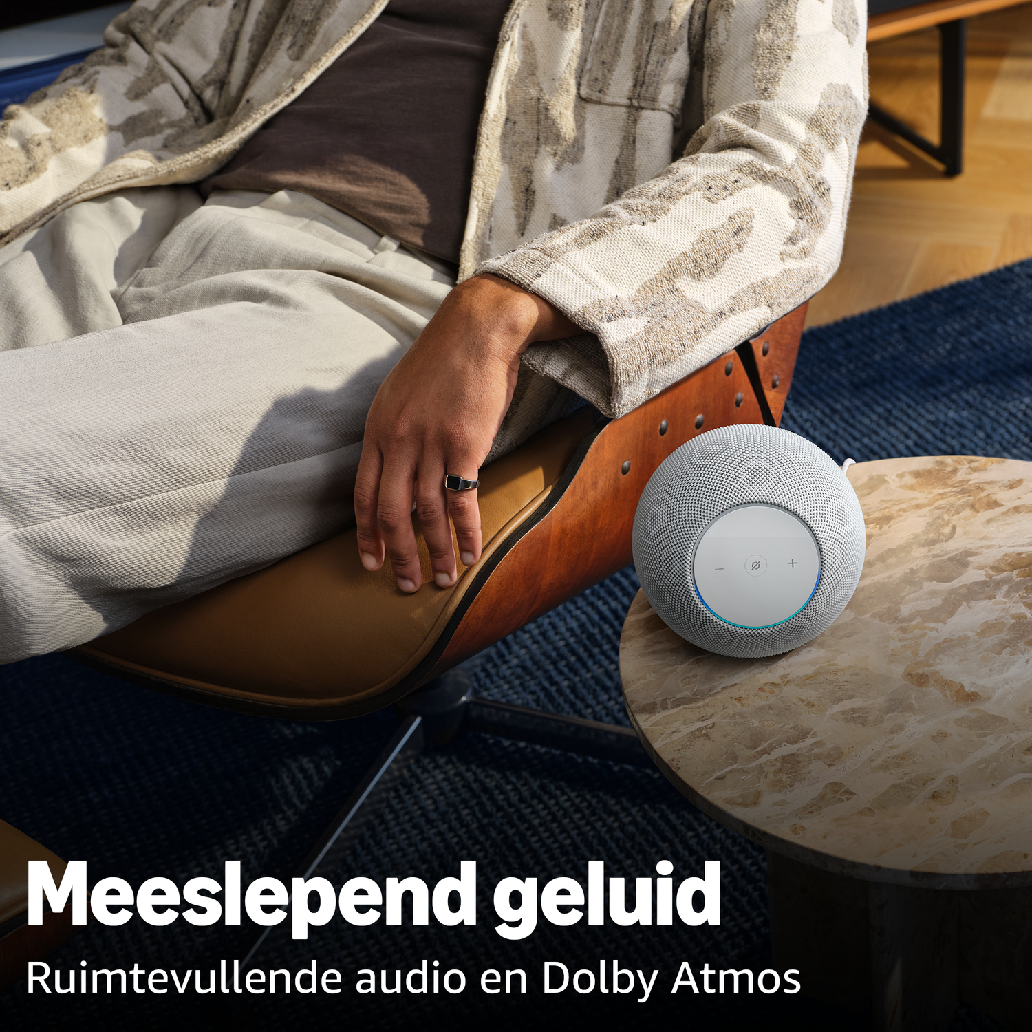 A white speaker sits on a marble table next to a person.