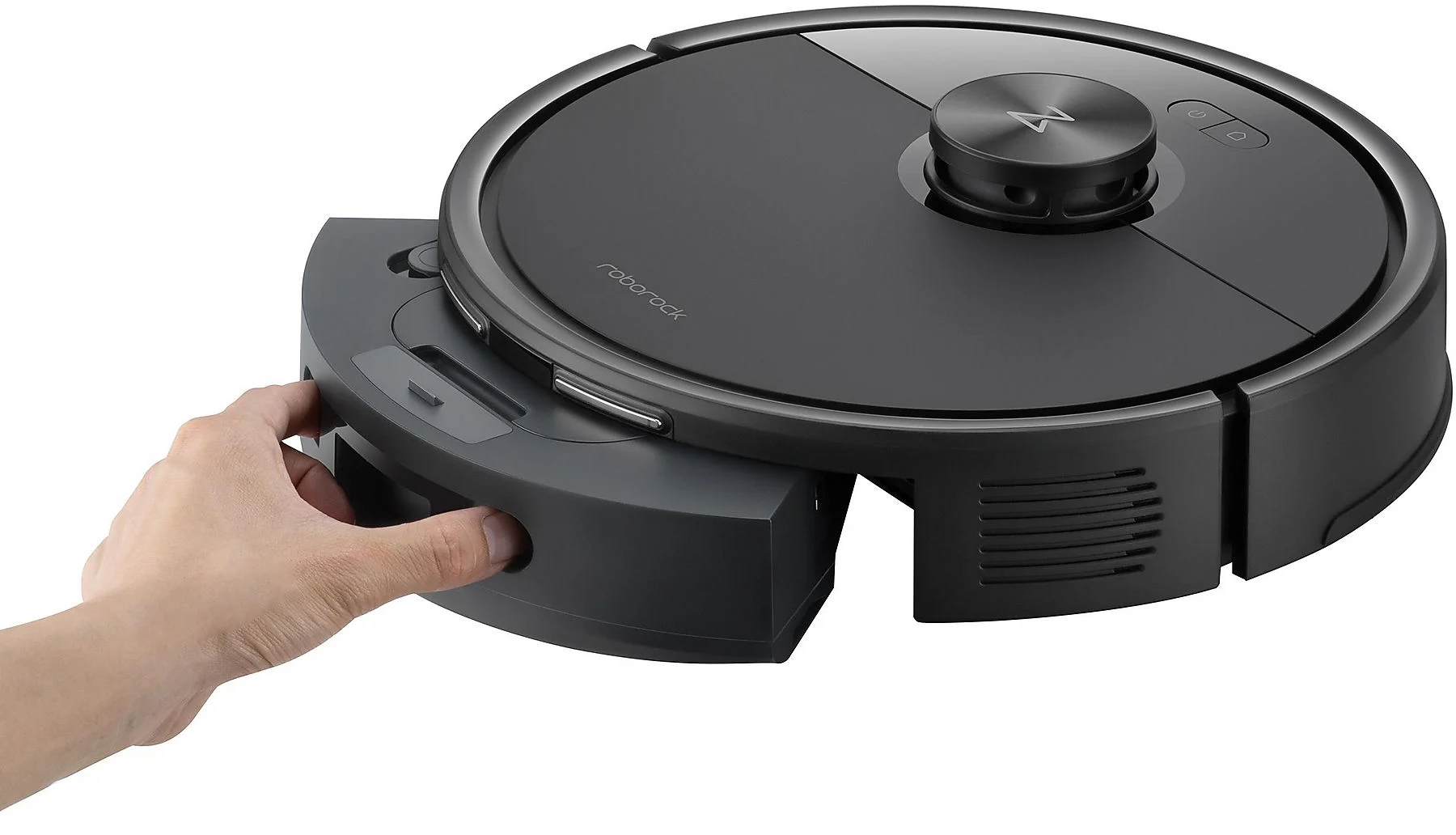 Une main retire un aspirateur robot gris de sa station de charge.
