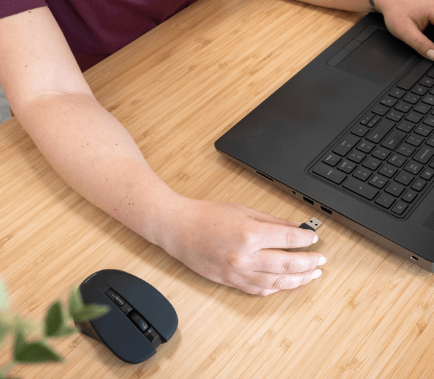 Egy kéz USB-kulcsot dug be egy laptopba, mellette egérrel.