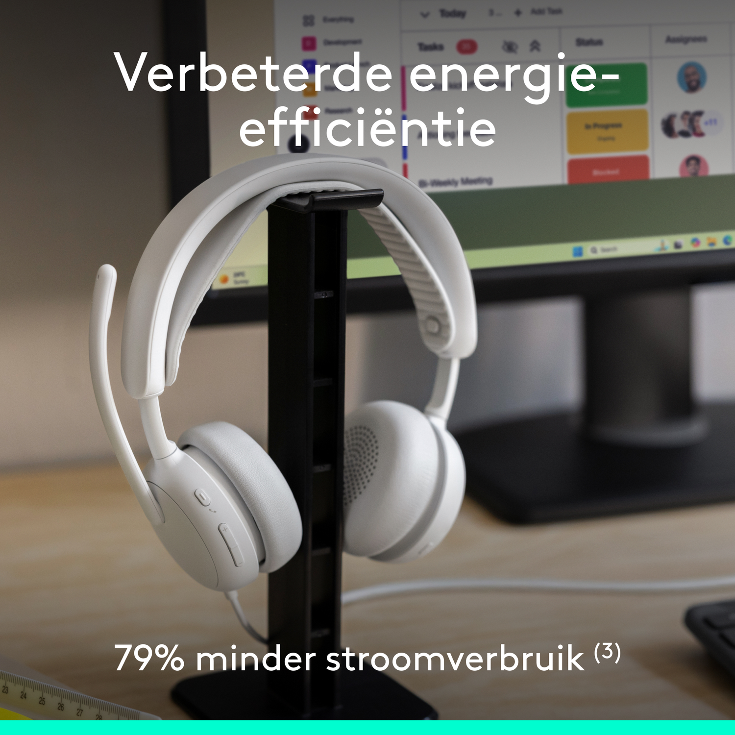 White headphones hang on a stand in front of a computer screen showing project management software.