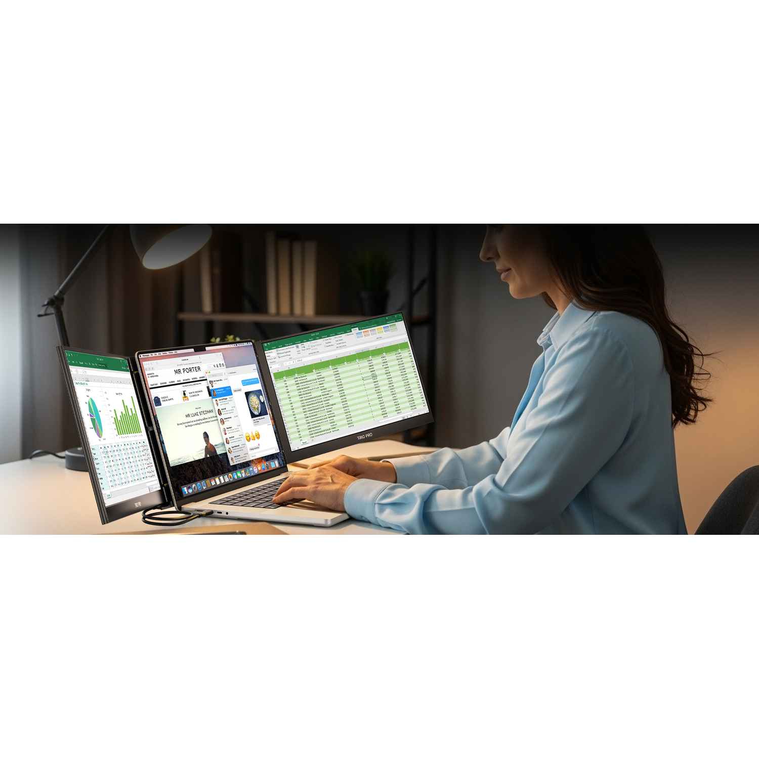 A woman works on a laptop with three external monitors. The desk is tidy.