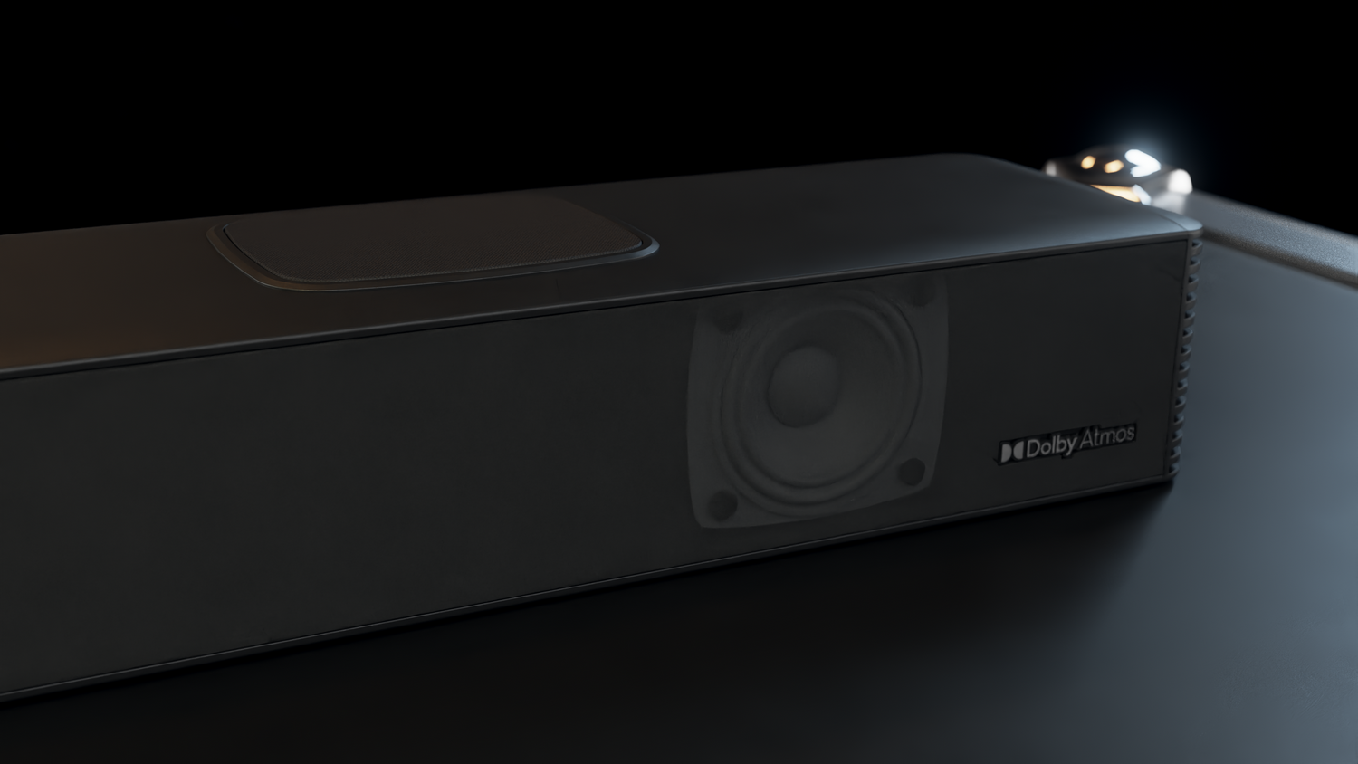 Barra de sonido Dolby Atmos negra con altavoz sobre fondo oscuro.