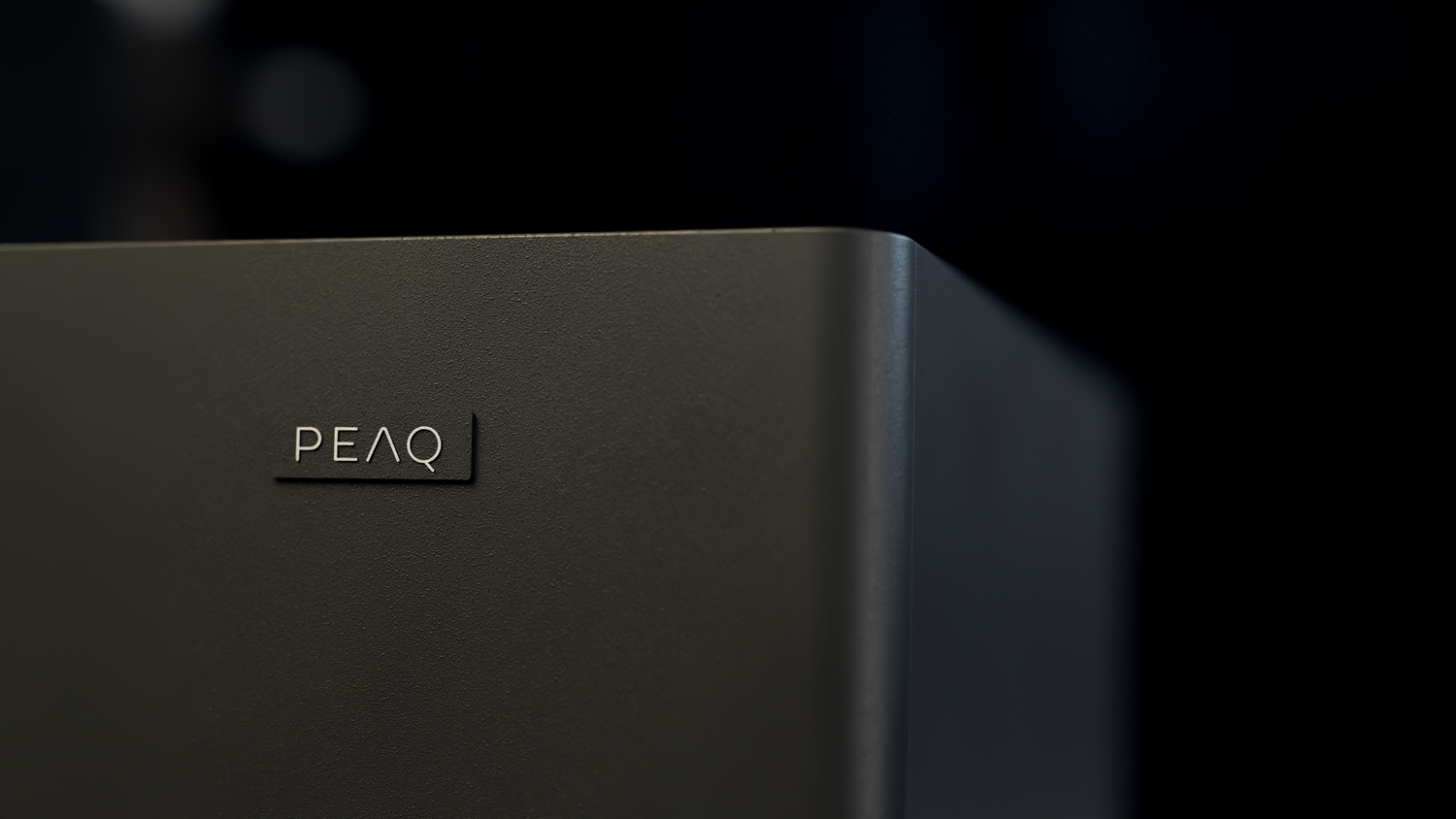 Caja negra con logo PEAQ. Fondo oscuro.