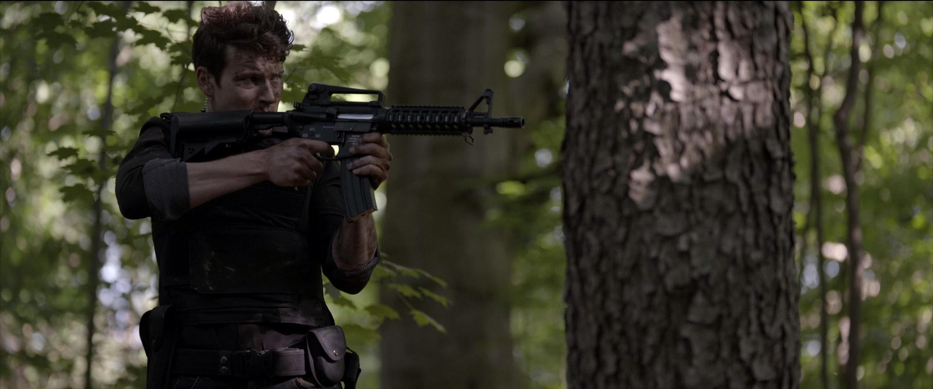 Ein Mann mit einem Gewehr im Wald.