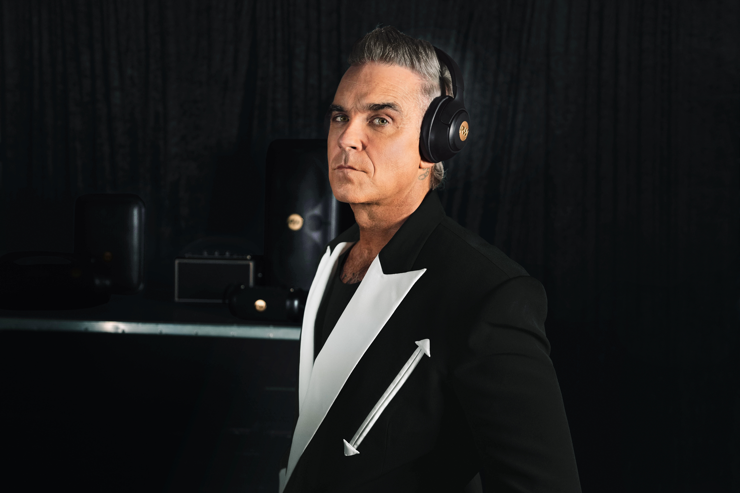 Hombre con auriculares en traje negro con detalles blancos.