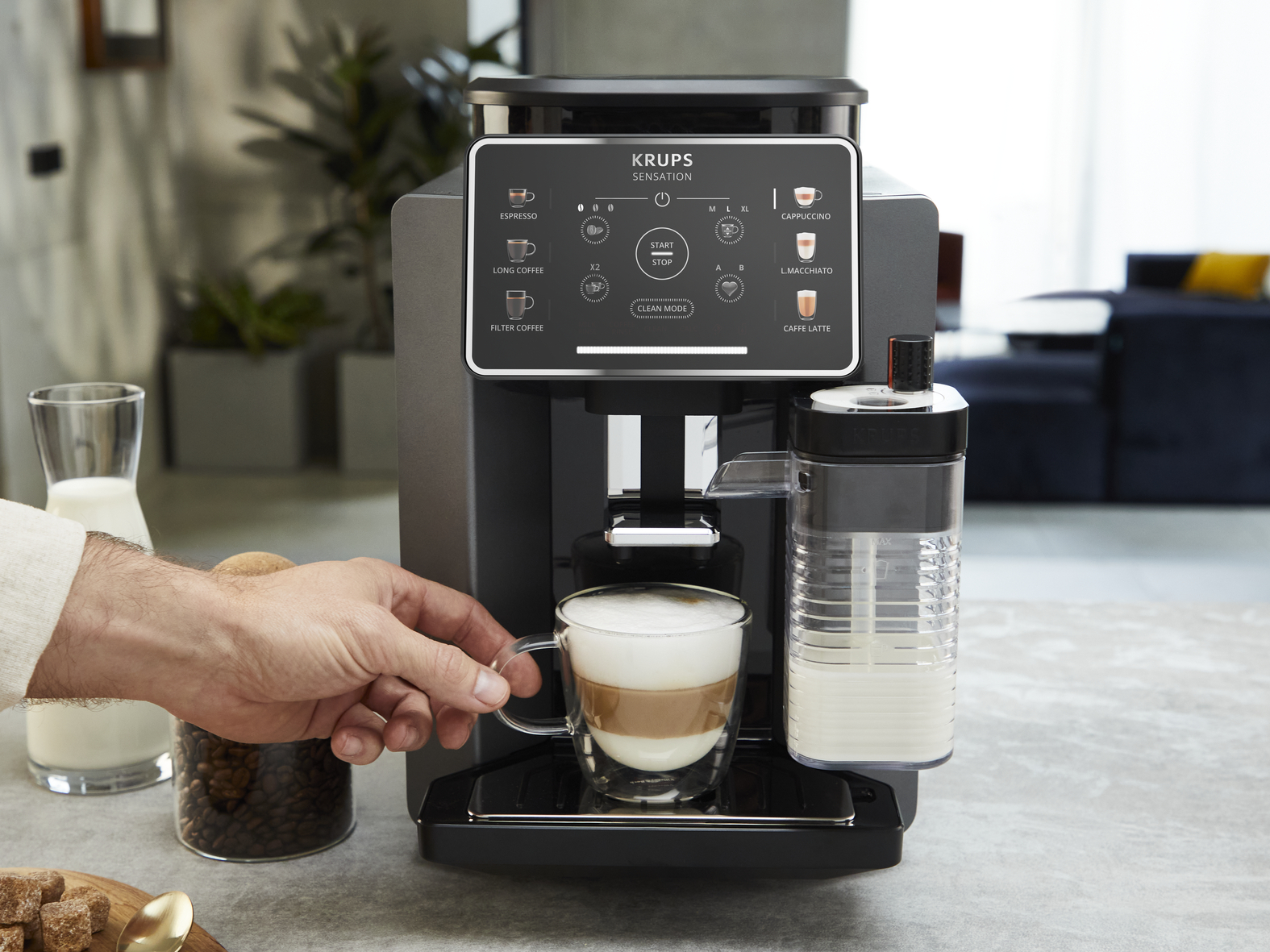 Koffiezetapparaat met melkreservoir en een glas koffie-melkdrank.