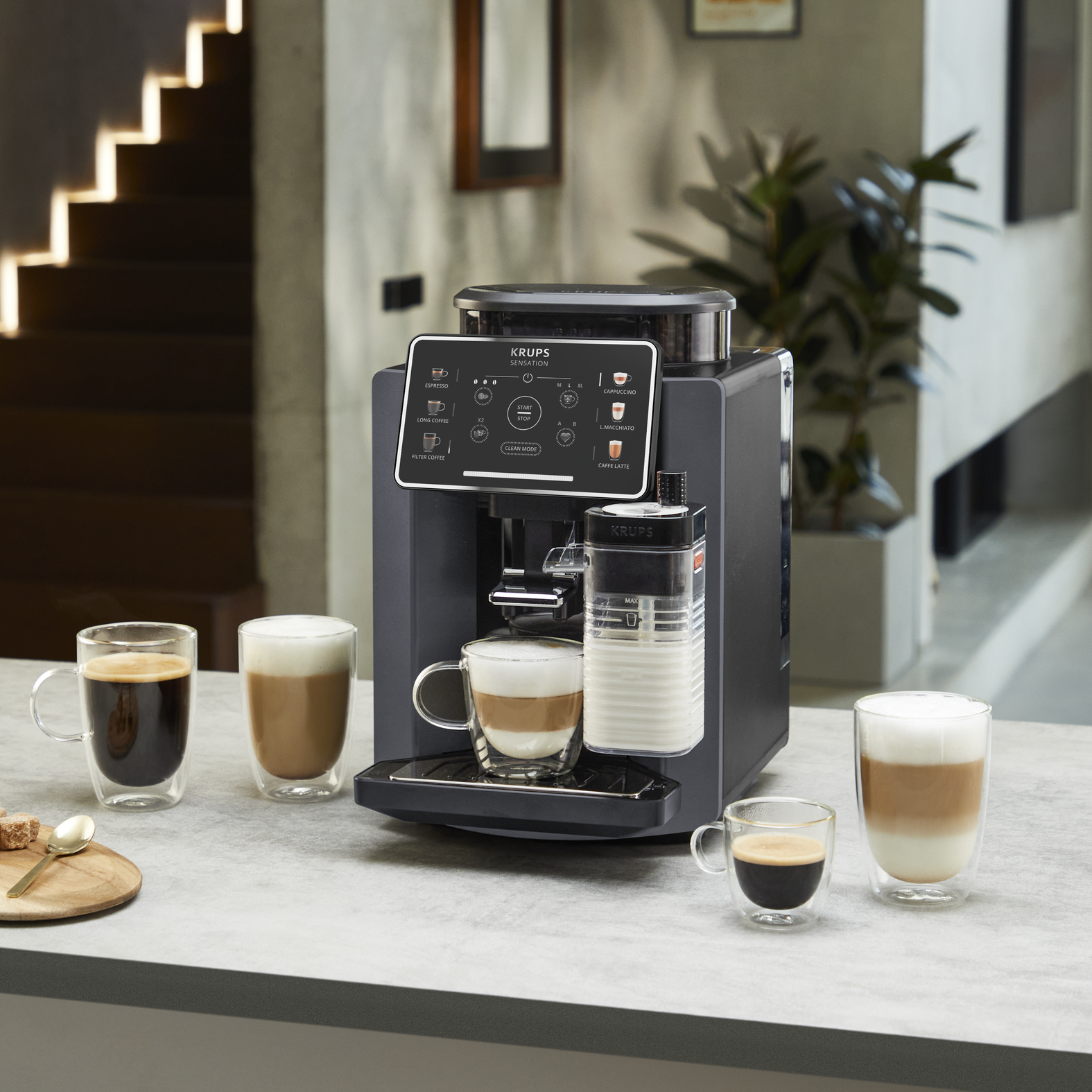 Een zwarte koffiemachine met melkreservoir en vier koffiedrankjes.