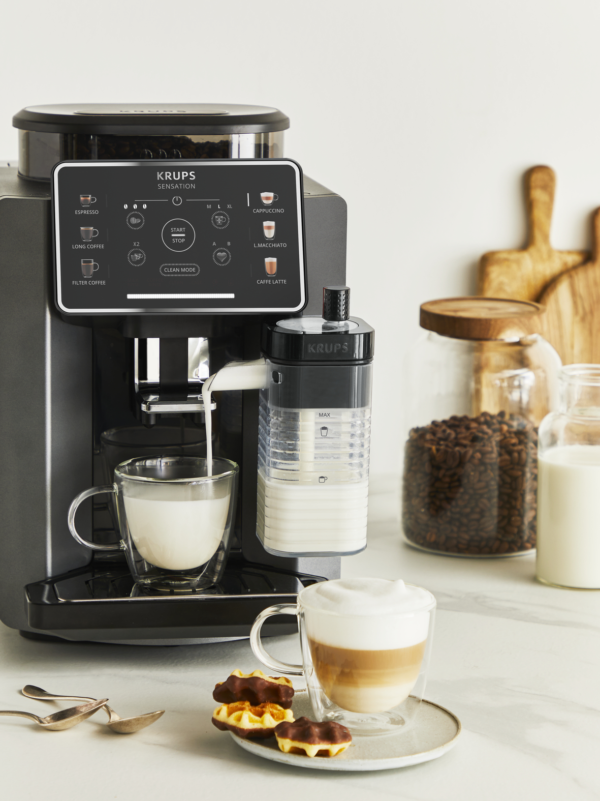Een koffiezetapparaat maakt een latte, met koekjes ernaast.