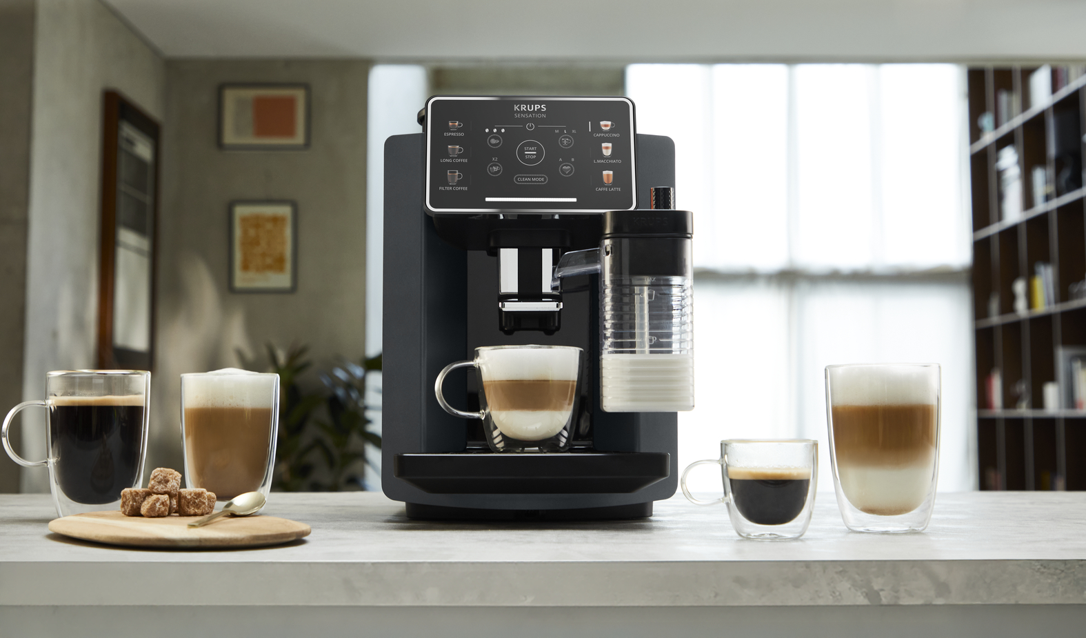 Krups volautomatische koffiemachine met melkreservoir en drie kopjes koffie.