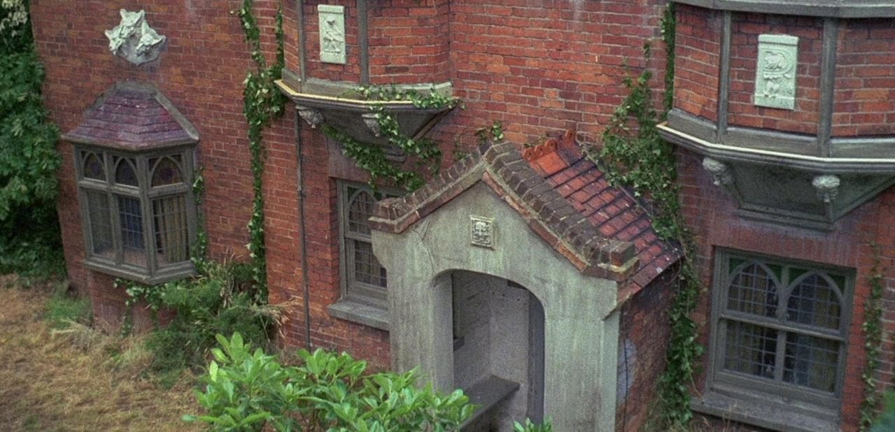 Ein altes Backsteinhaus mit Efeubewuchs und verzierten Fenstern.