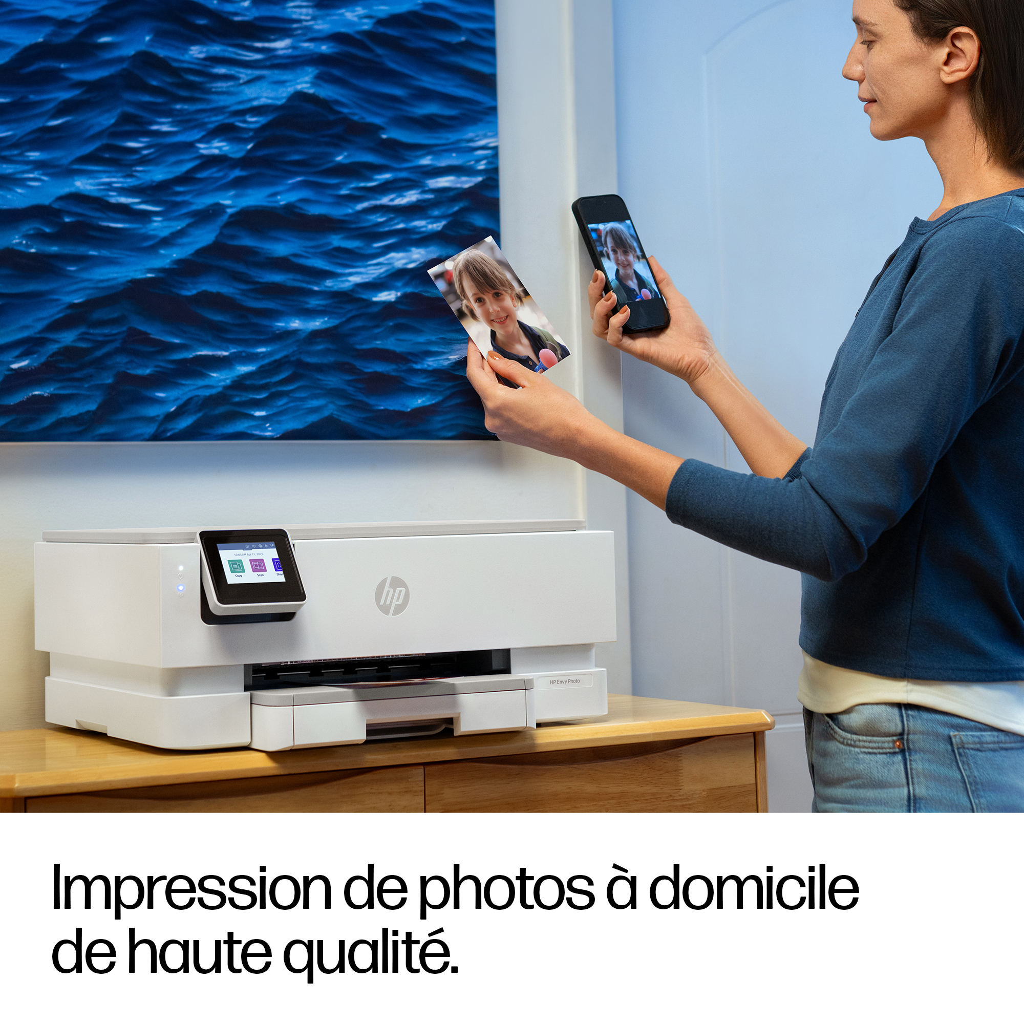 Una donna tiene una foto e uno smartphone davanti a una stampante.