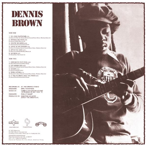 Dennis Brown spielt Gitarre und trägt ein Sweatshirt mit einem Wappen.