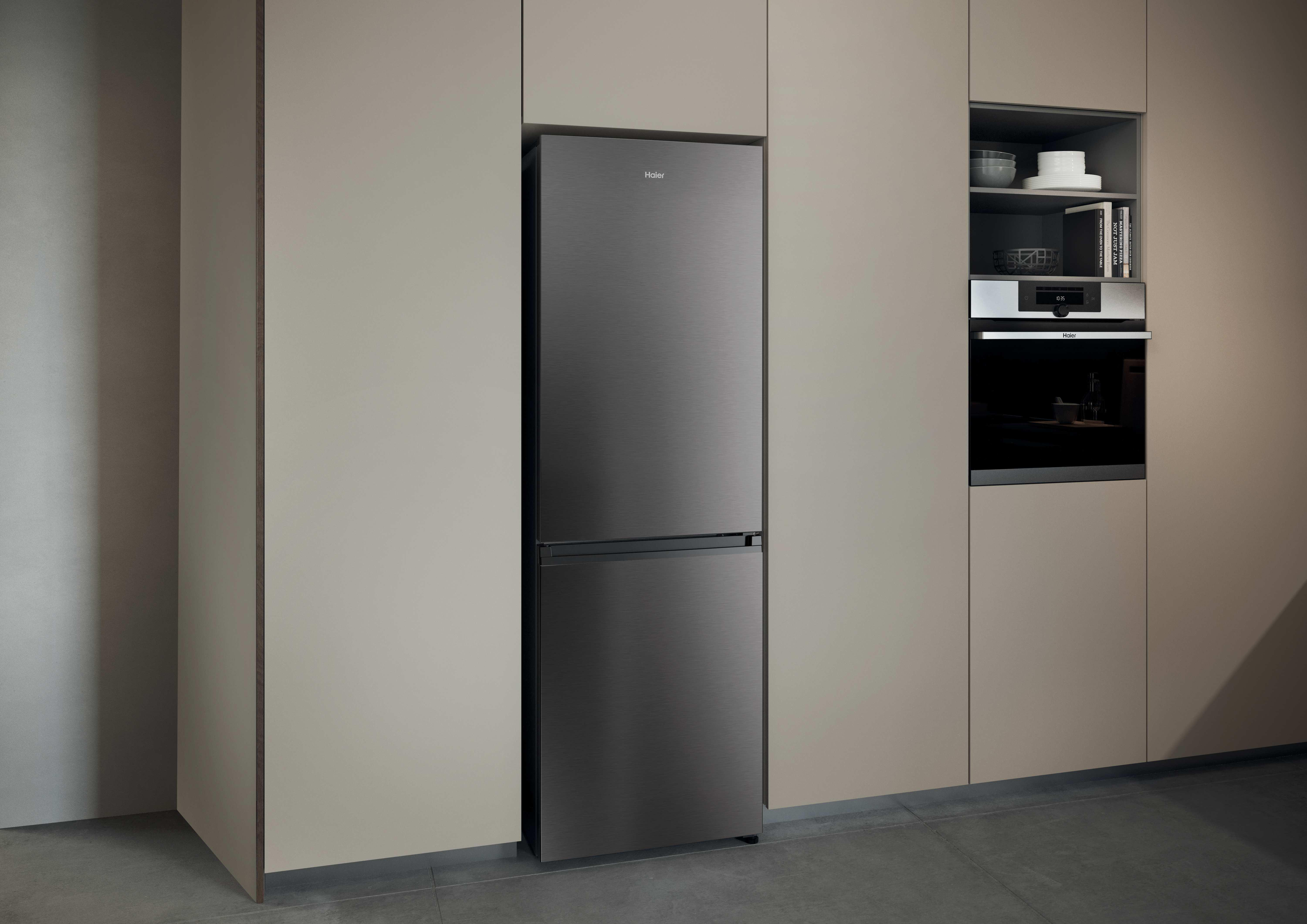 Ein dunkler Haier Kühlschrank neben einem Einbauofen in einer modernen Küche.