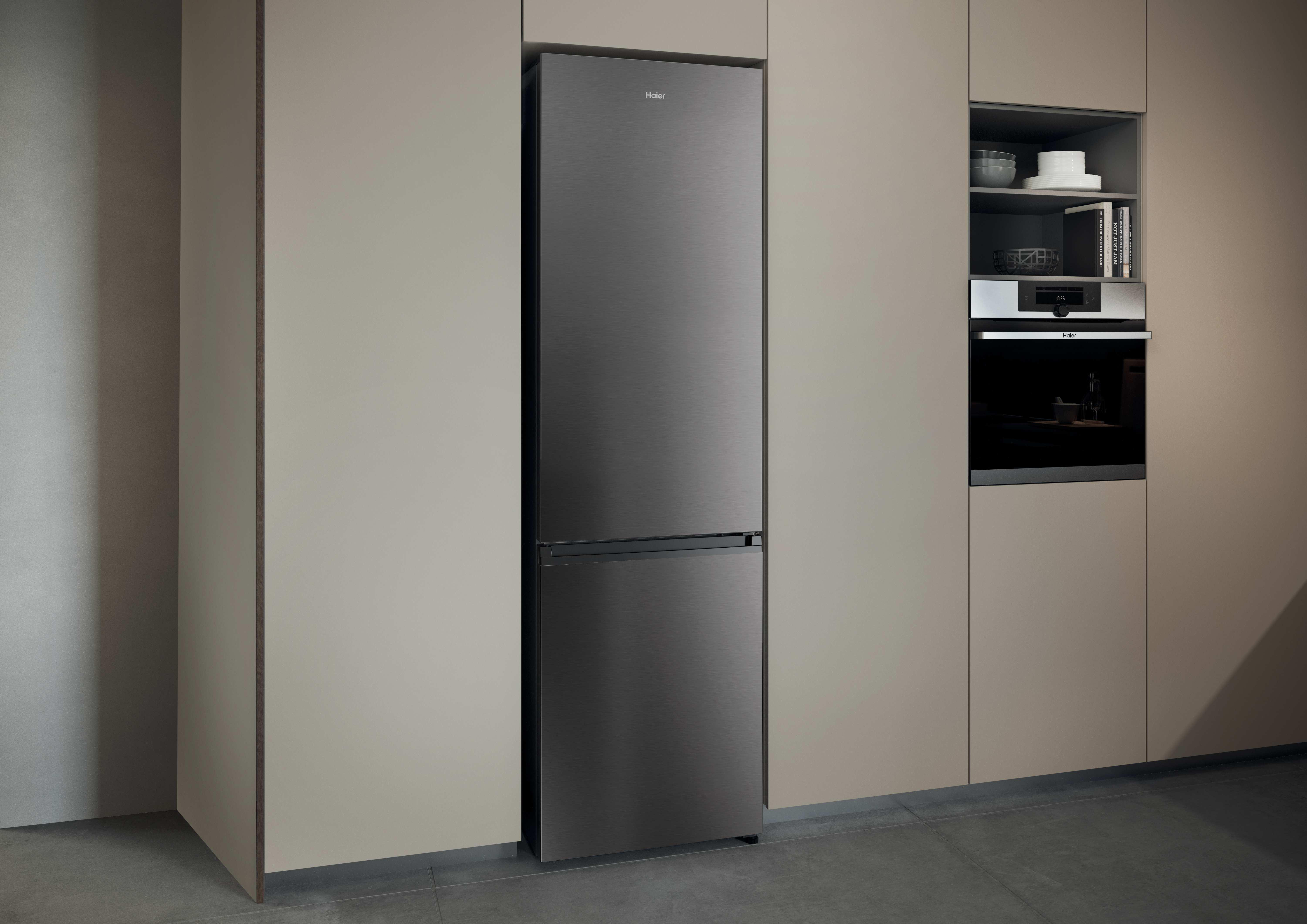 Ein dunkler Kühlschrank steht neben einem eingebauten Ofen in einer modernen Küche.