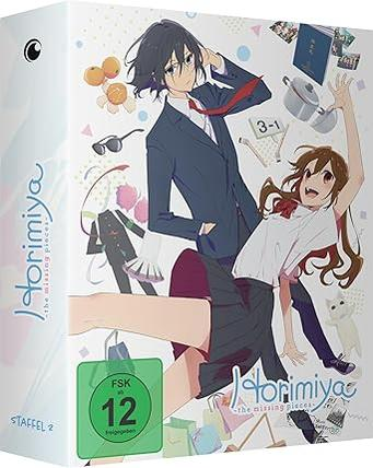 Anime-Box mit zwei Hauptfiguren, Orangen, Sonnenbrille, Kochtopf und Einkaufstaschen.