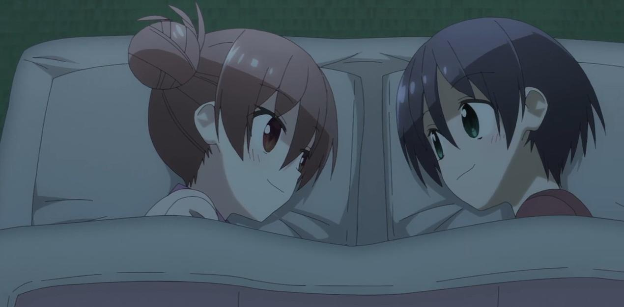 Zwei Anime-Mädchen liegen im Bett und lächeln sich an.