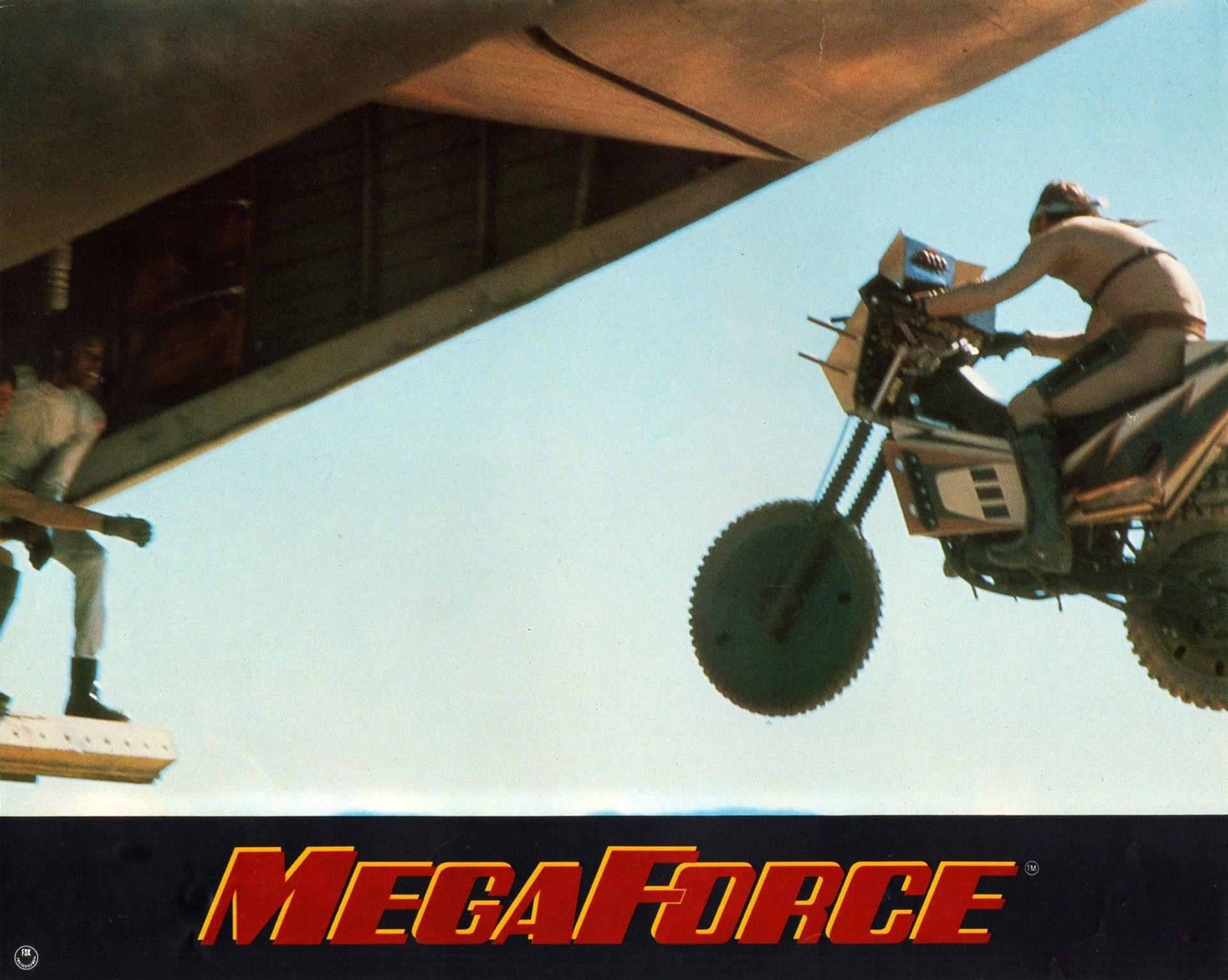 Mann auf Motorrad springt von Flugzeug ab, Mega Force Schriftzug.