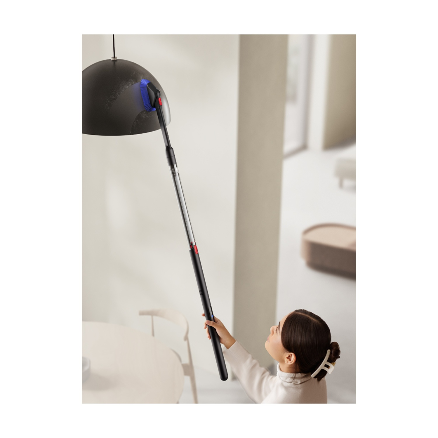 Una persona pulisce una lampada con un accessorio per aspirapolvere.