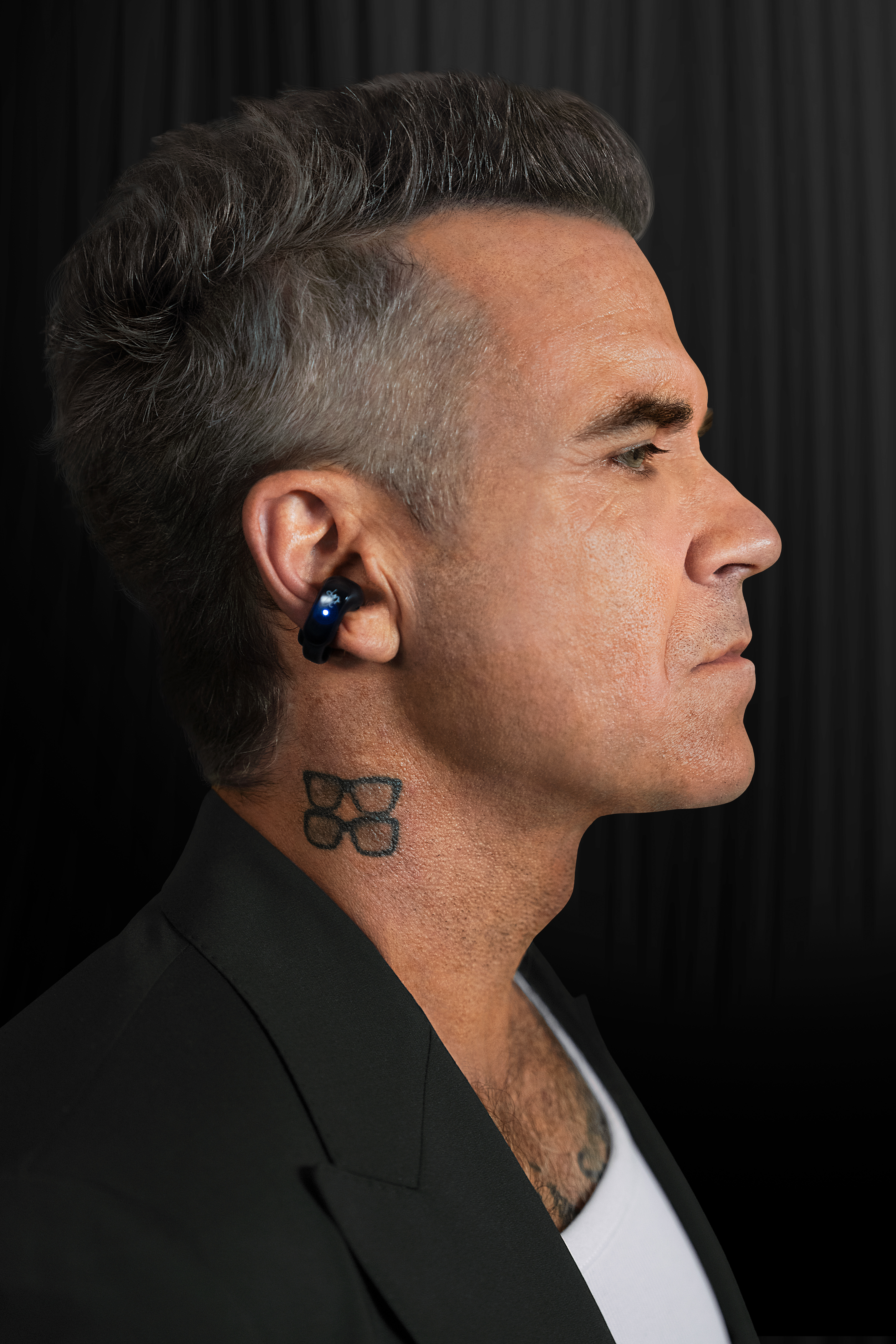 Mann mit blauem Ohrhörer und Brillen-Tattoo am Hals.