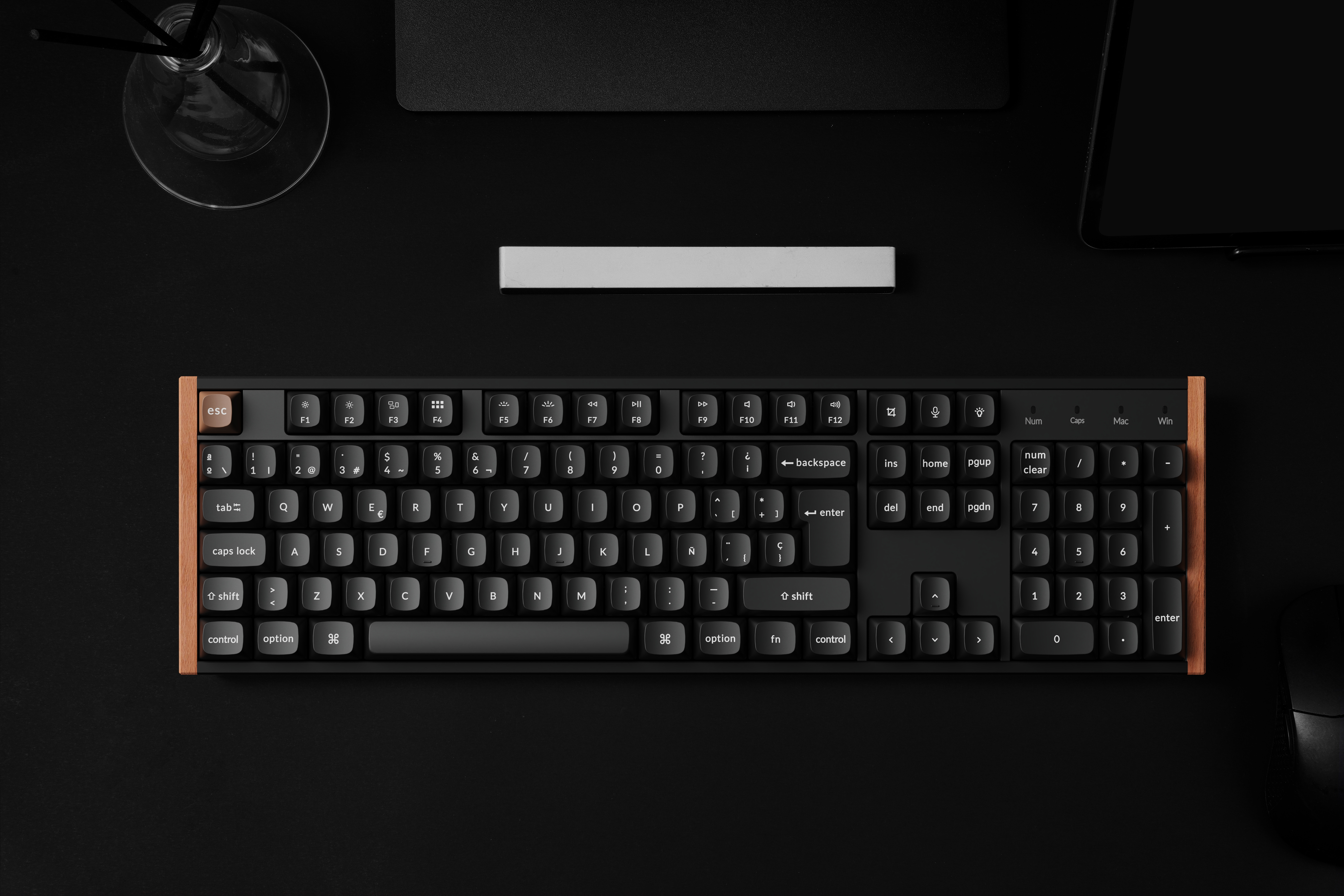 Schwarze Tastatur mit Holzrahmen auf schwarzem Schreibtisch, Draufsicht.