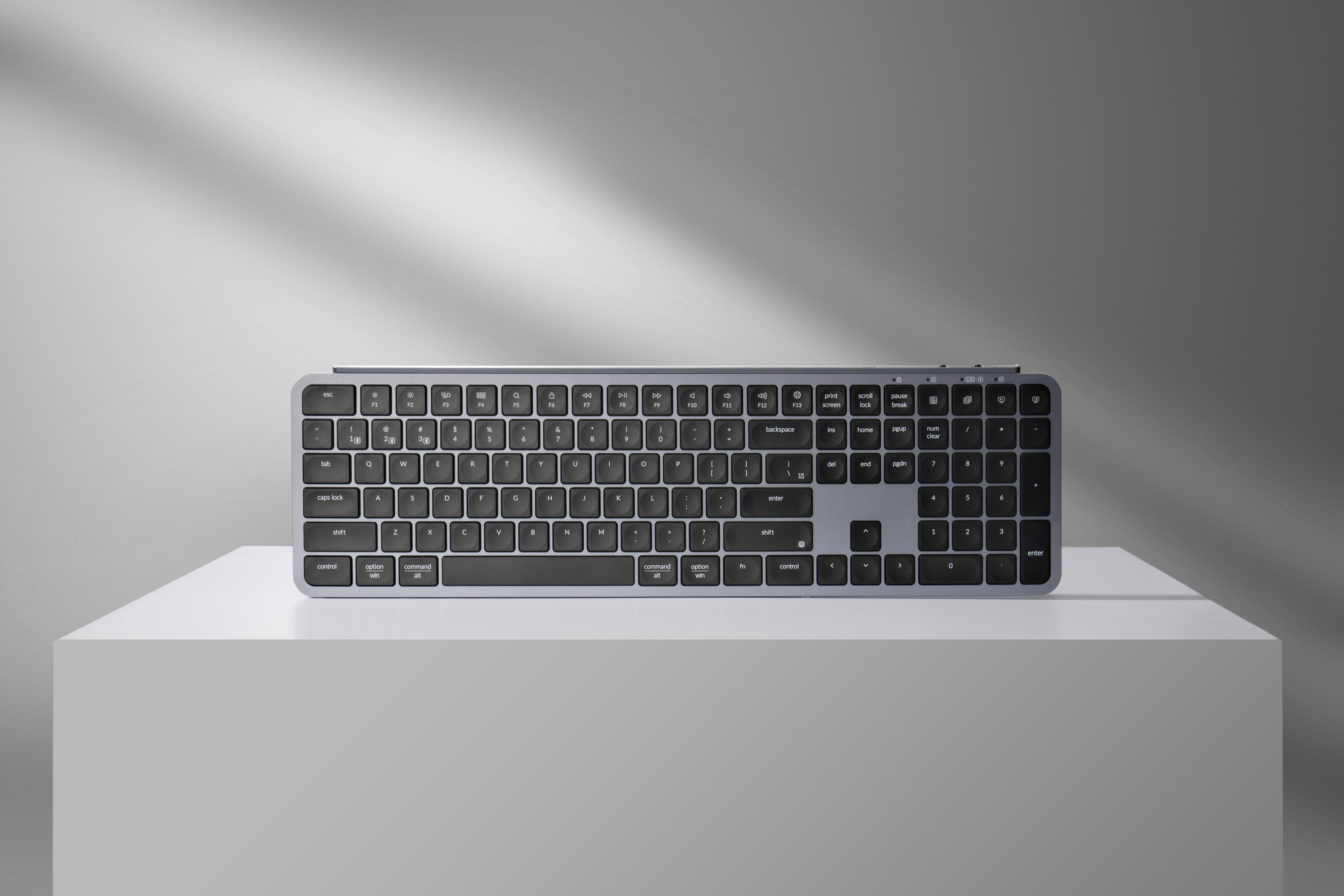 Eine graue Tastatur mit Nummernblock auf einem weißen Podest.