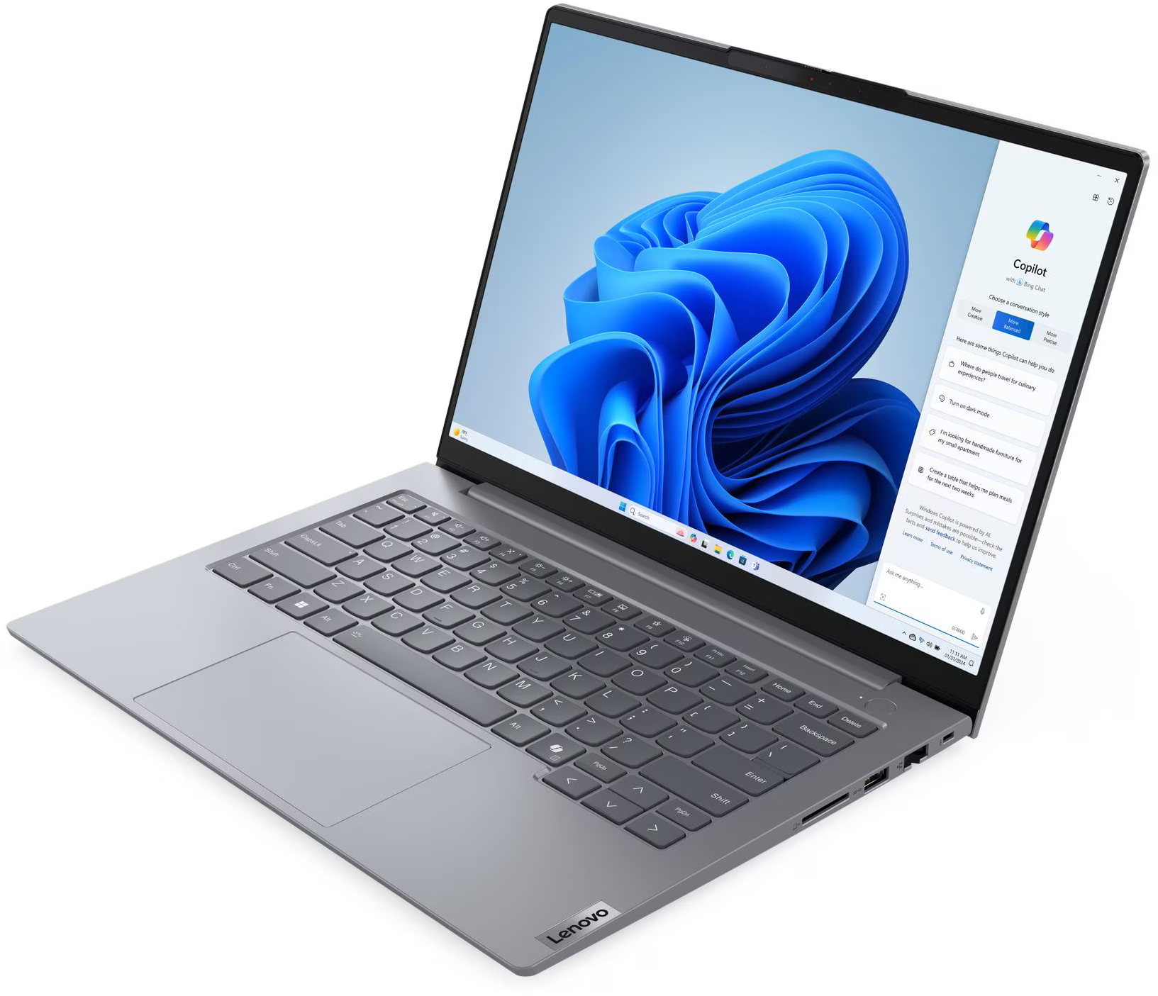 Egy ezüst laptop kék háttérképpel és nyitott Copilot ablak.