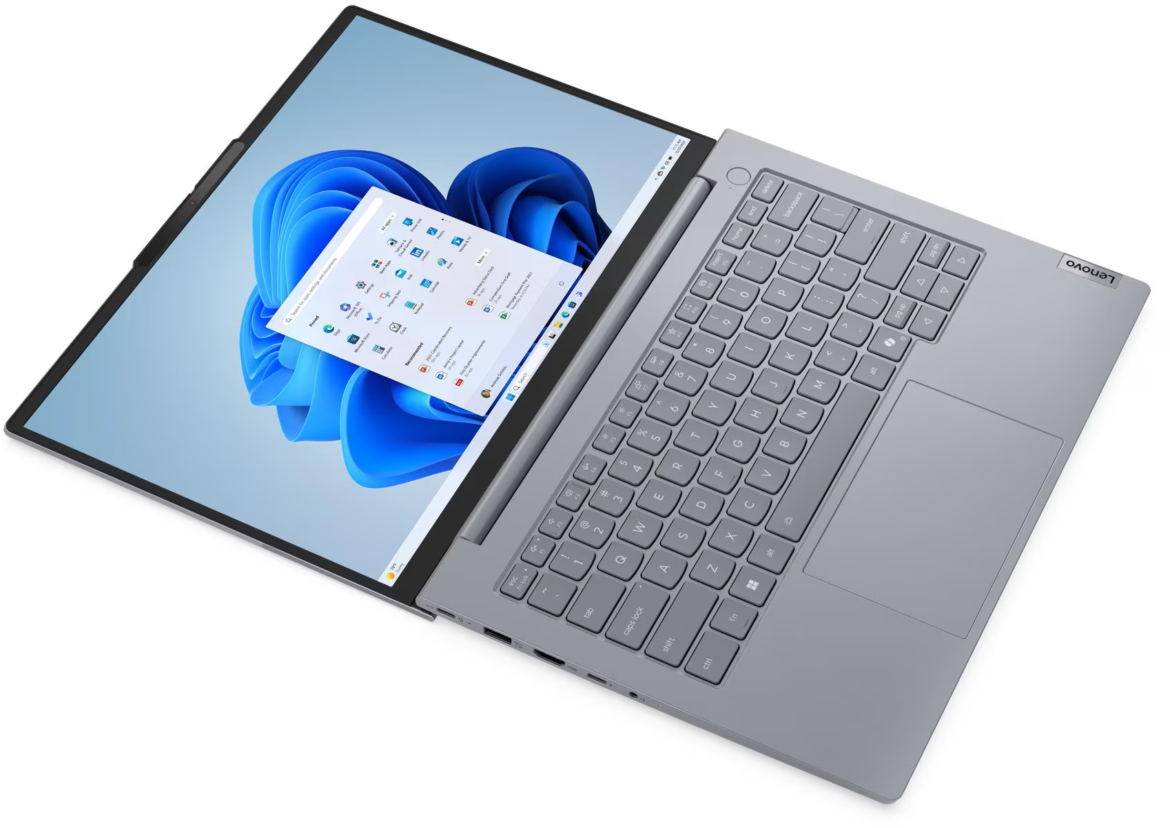 Egy szürke Lenovo laptop, nyitott állapotban, Windows 11 start menüvel a képernyőn.